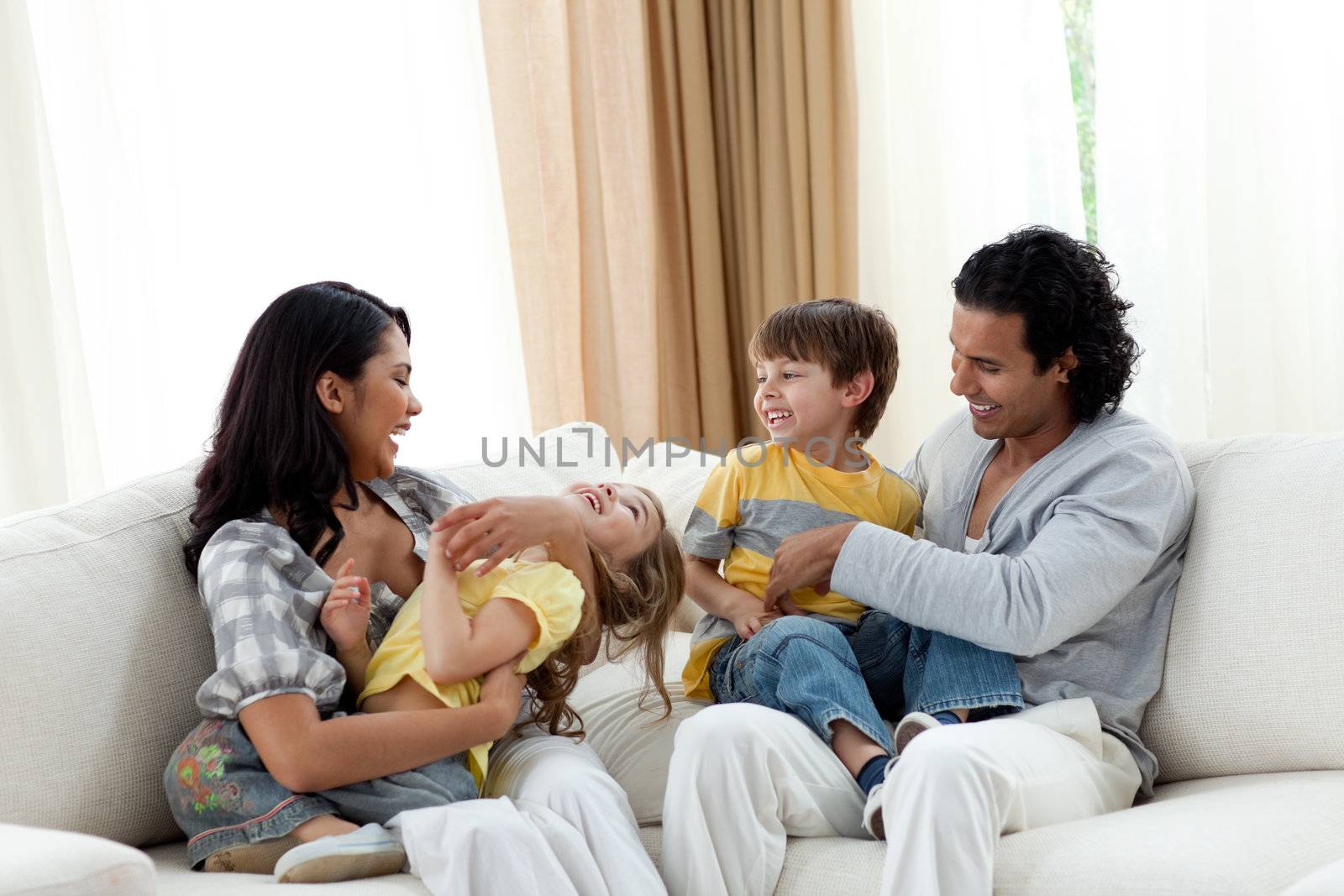 Earing parents playing with their children on sofa at home