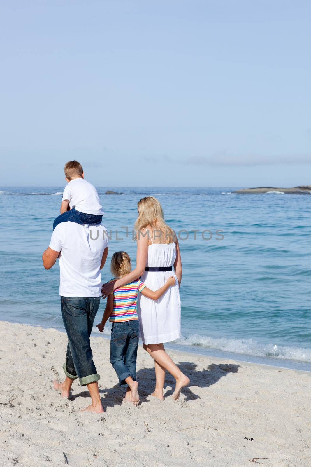 Cheerful family walking on the sand at the beach 