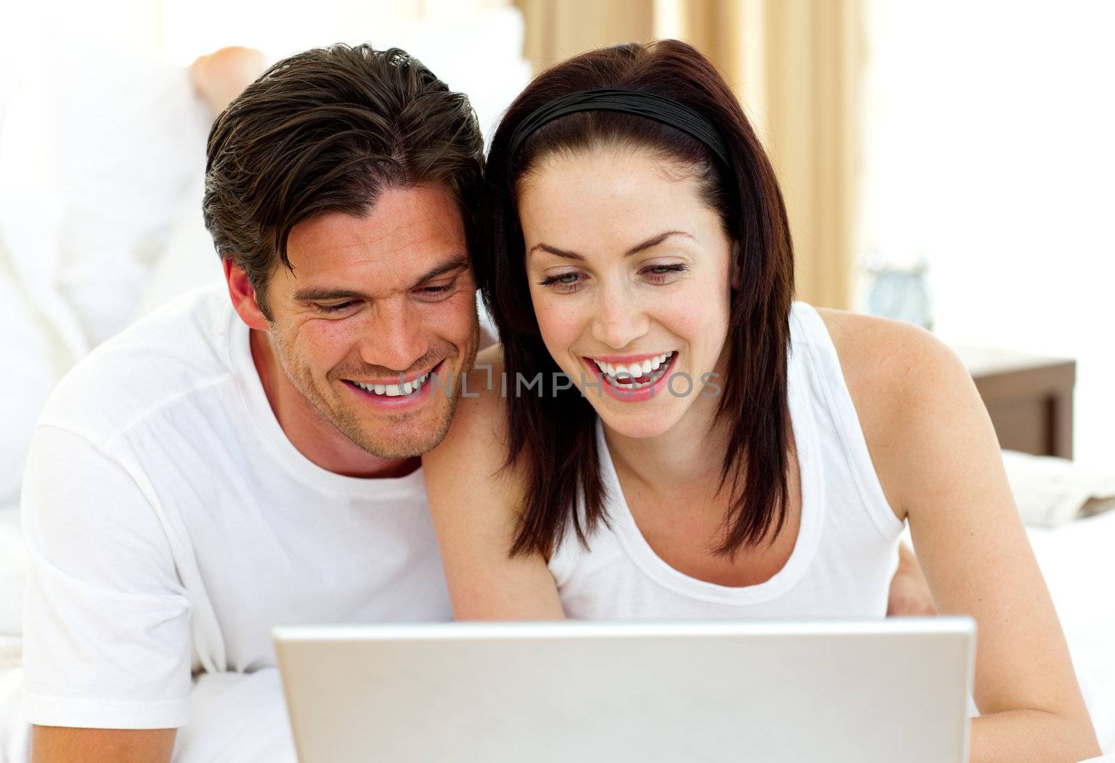 Romantic couple using laptop lying on the bed