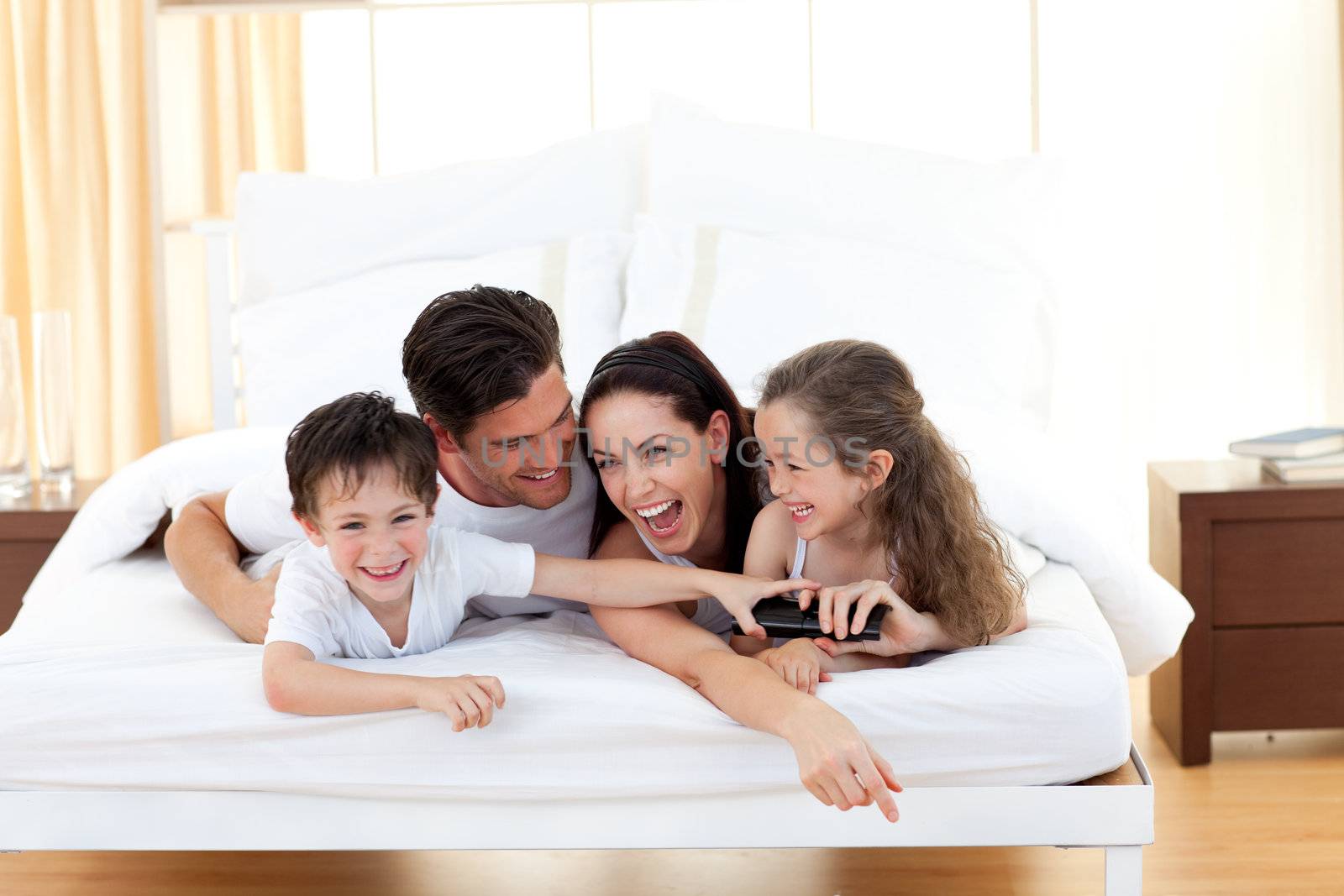 Siblings with their parents having fun lying on the bed