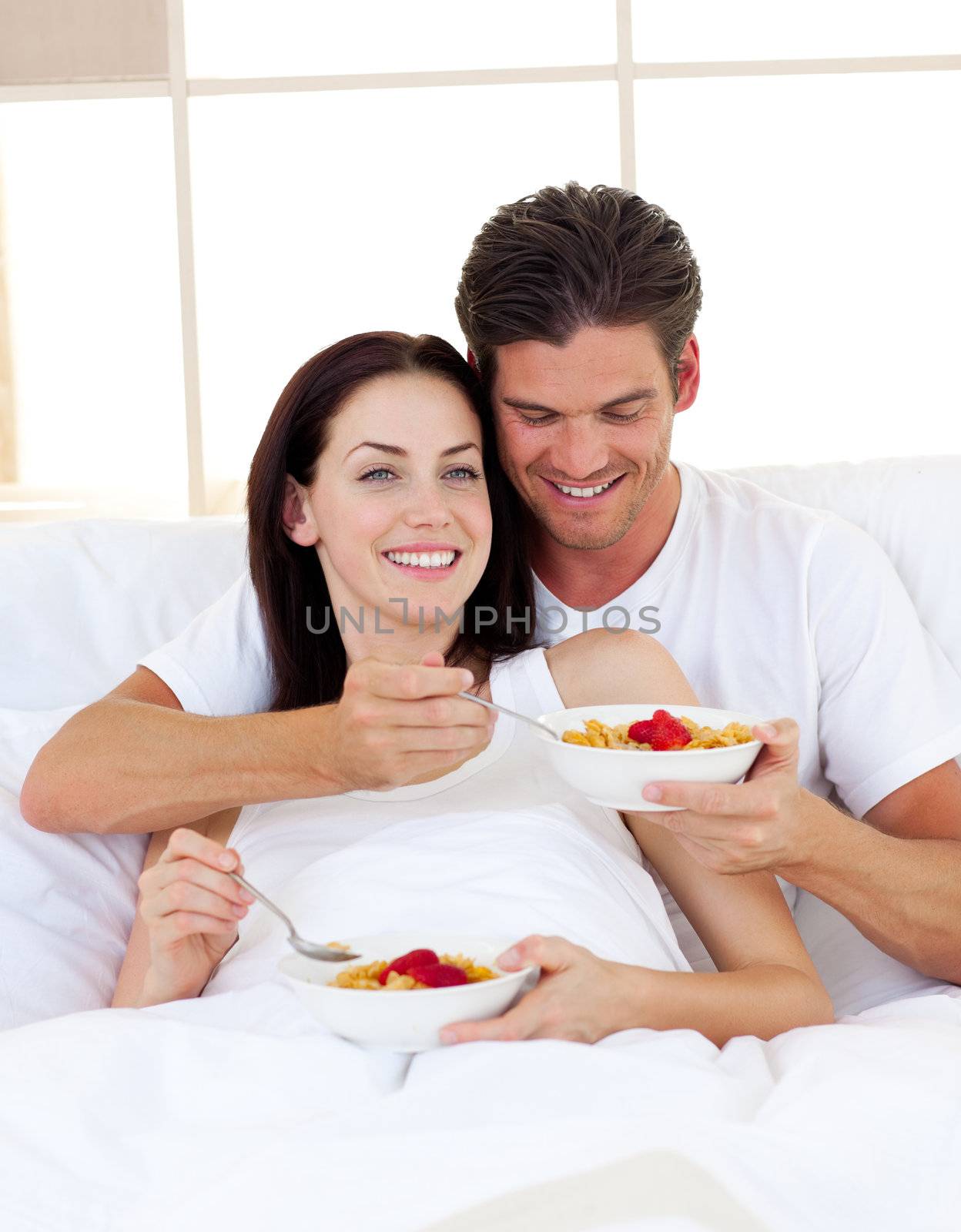 Romantic couple having breakfast lying in the bed