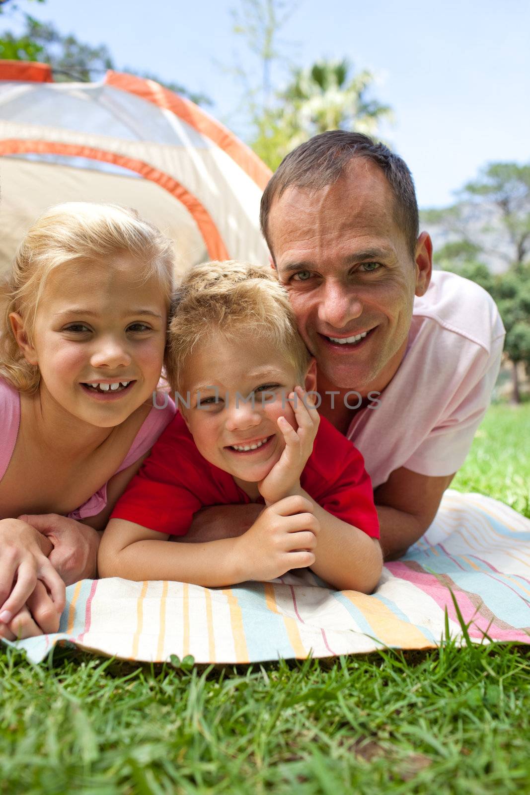 Happy father and his children lying on the grass in a park