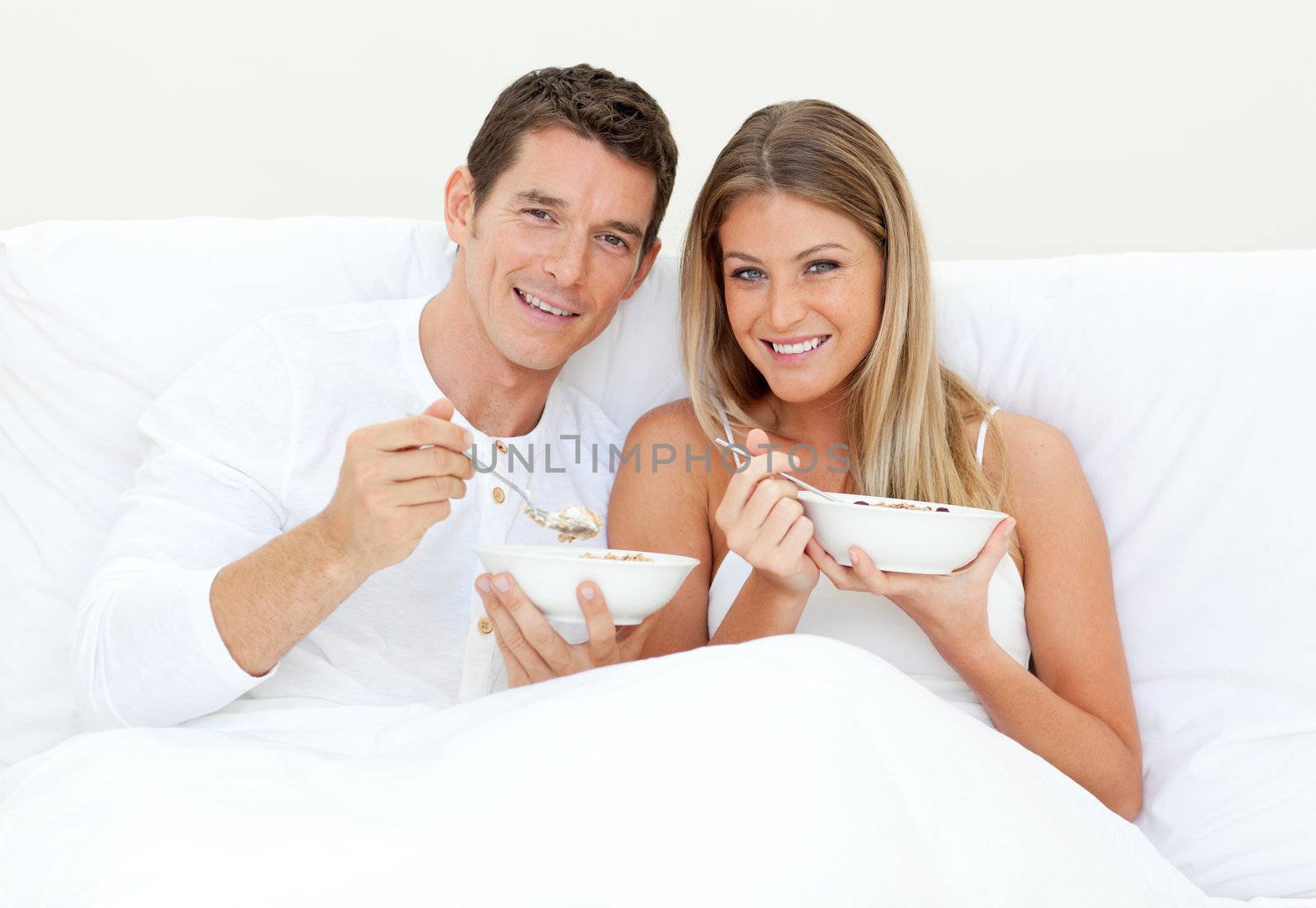 Loving couple having breakfast lying on their bed. Concept of love.