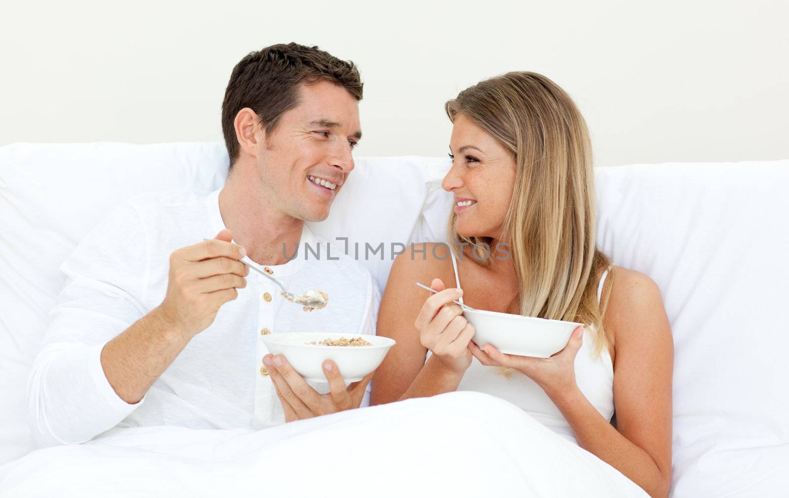 Affectionate couple having breakfast lying on their bed by Wavebreakmedia