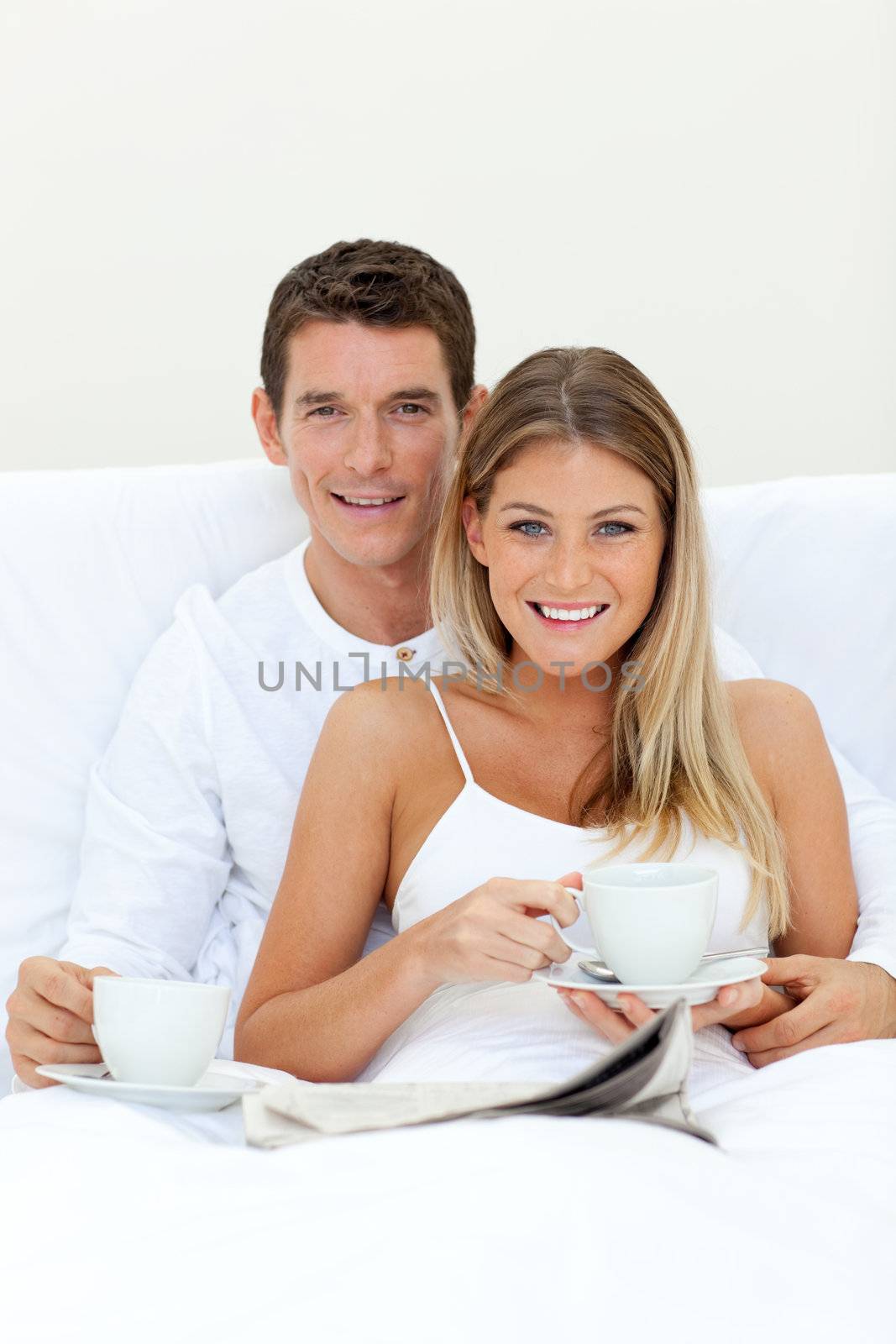 Romantic couple drinking coffee lying on their bed. Concept of love.