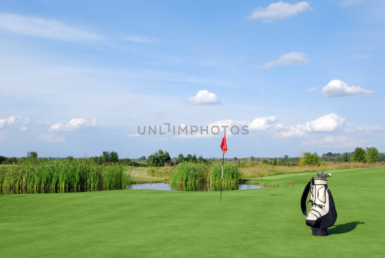 Golf field with red flag and white golf bag