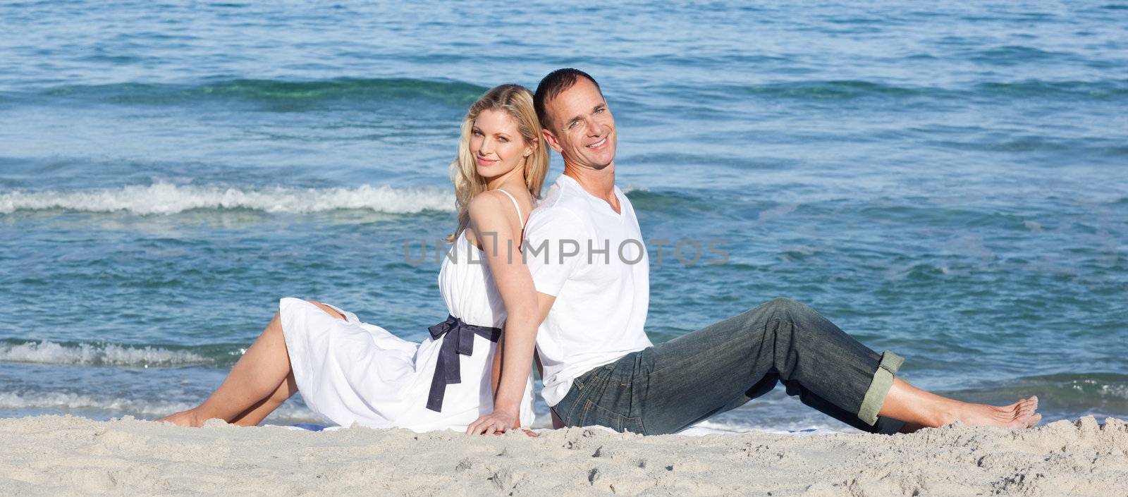Portrait of couple sitting on sand at the beach