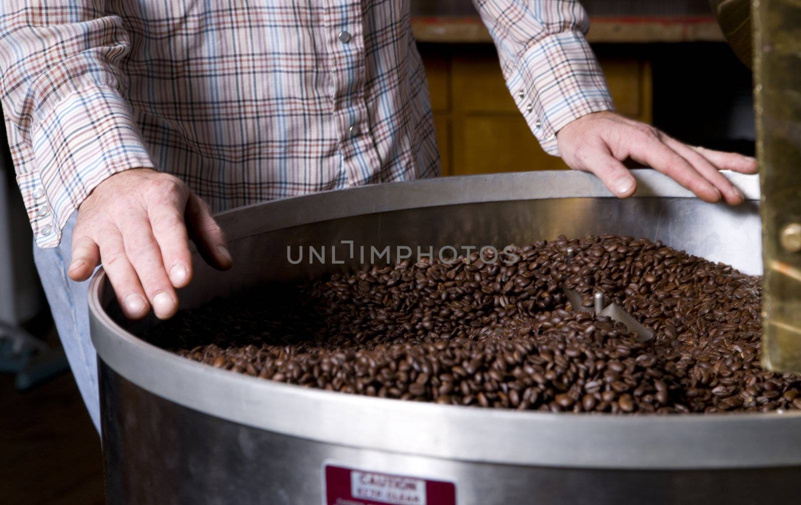 A coffee roaster labors over the cooling bin