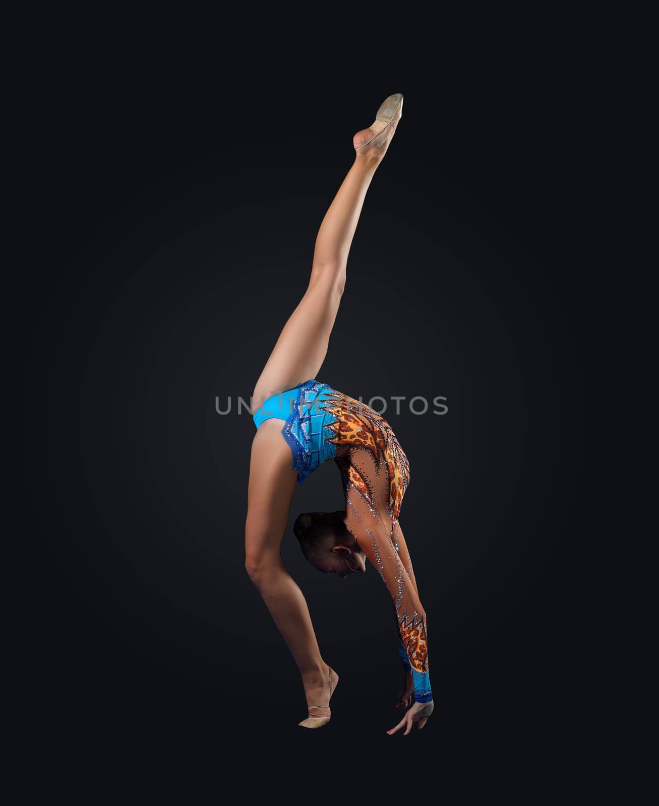 Young cute woman in gymnast suit show athletic skill on black background