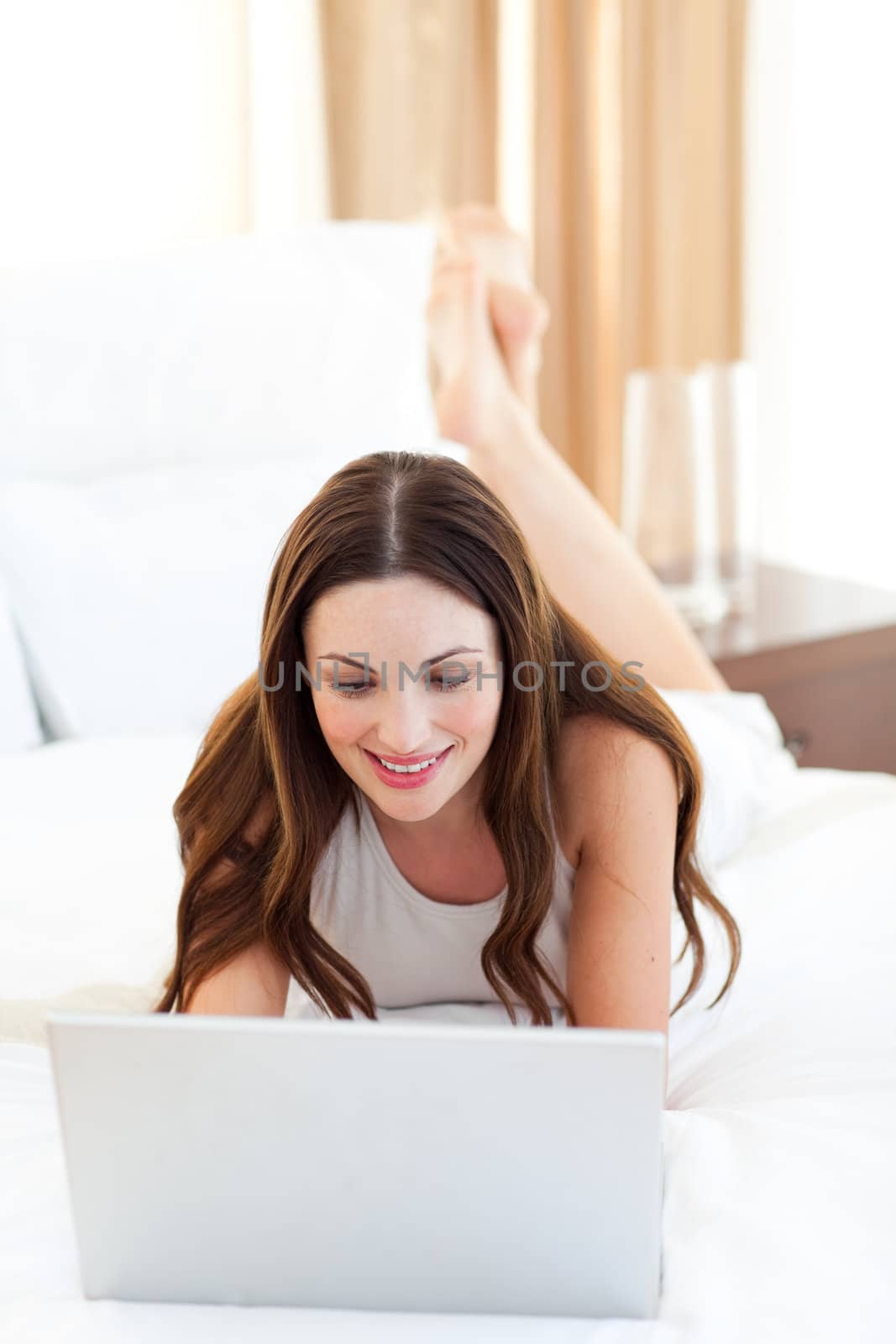 Attractive woman using her laptop lying on bed in the bedroom