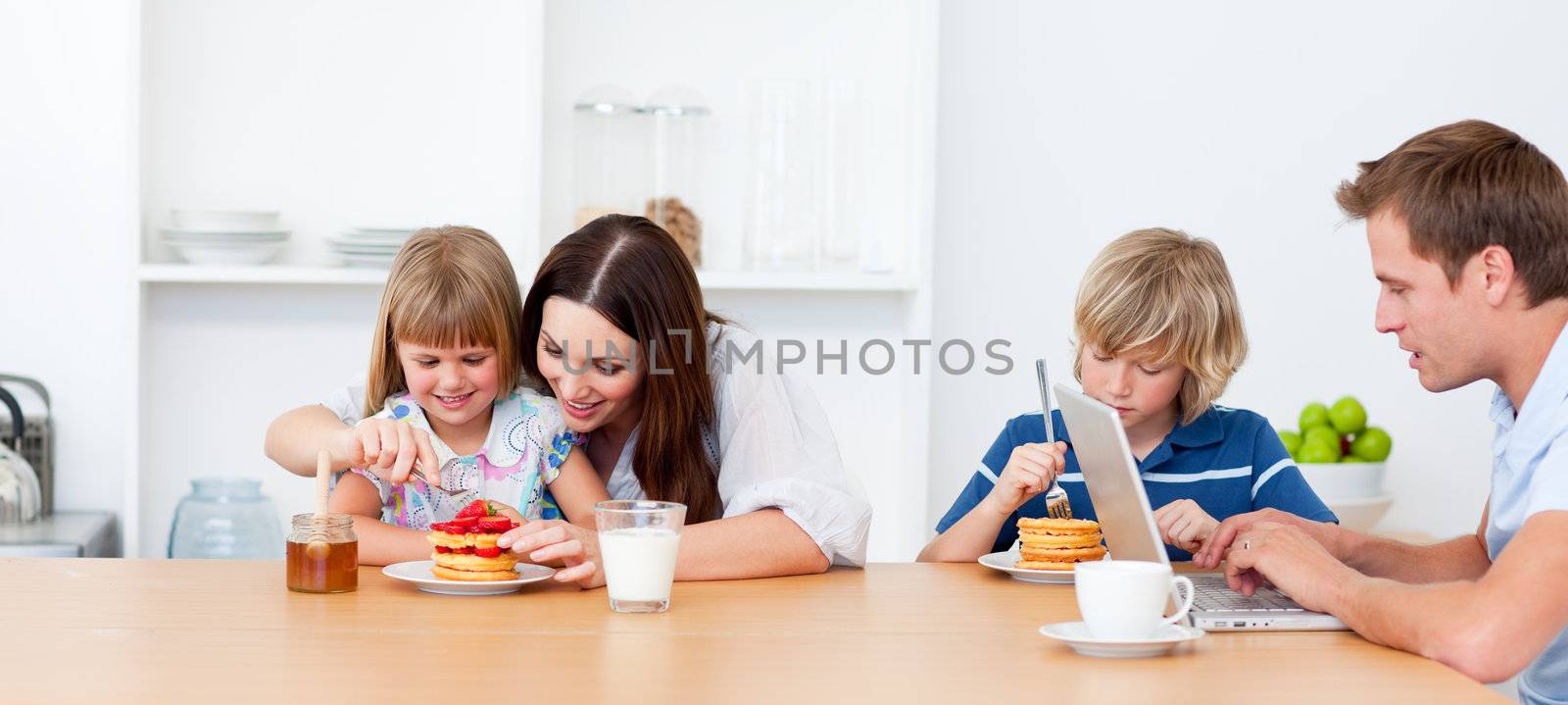 Merry family eating breakfast in the kitchen at home