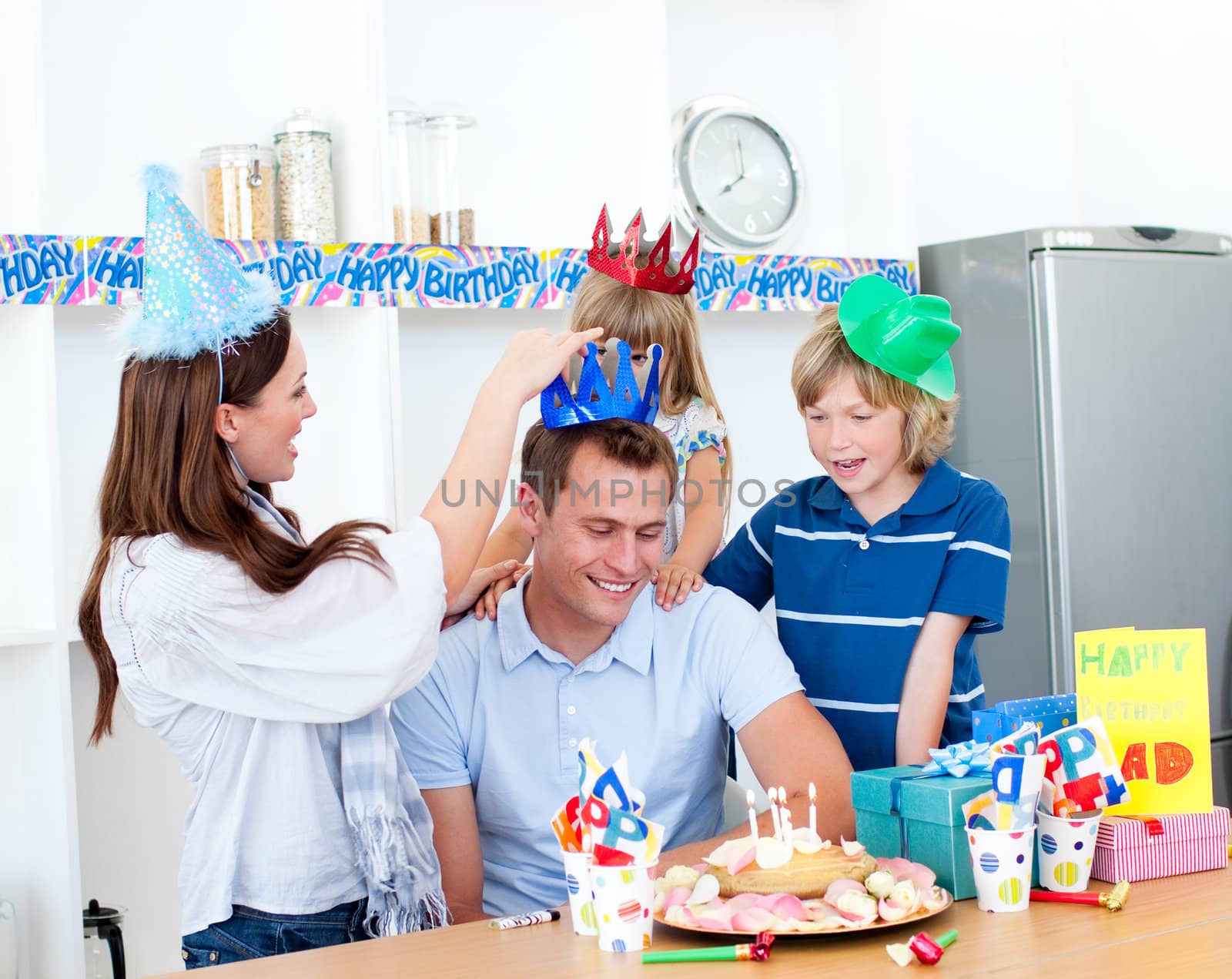 Delighted man celebrating his birthday with his wife and his children in the kitchen