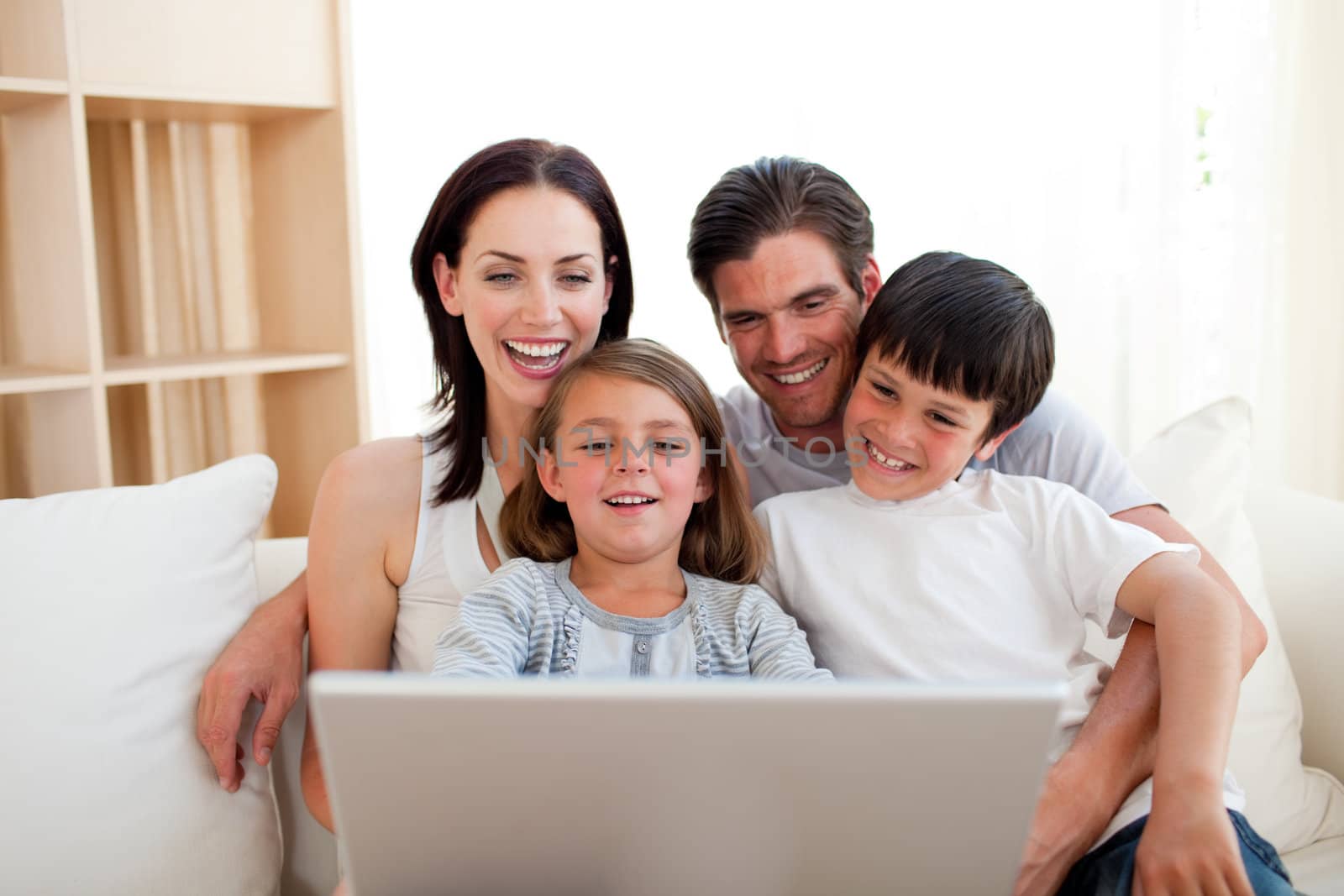 Smiling fanily using a laptop on the sofa at home