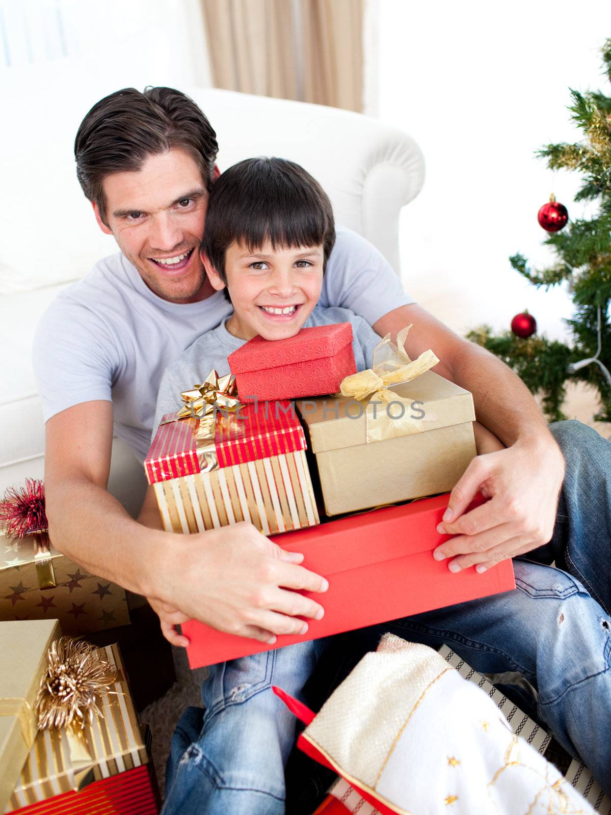 Happy father and son holding Christmas presents at home