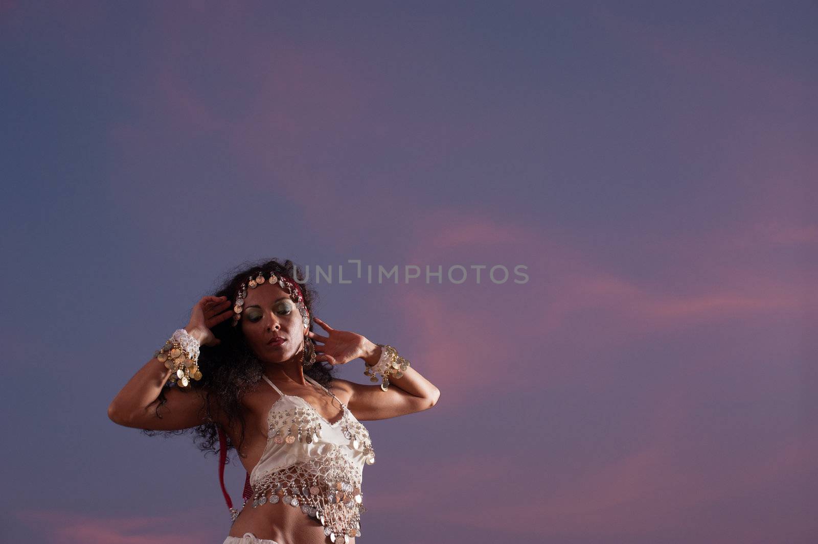 Attractive oriental dancer against an evening sky