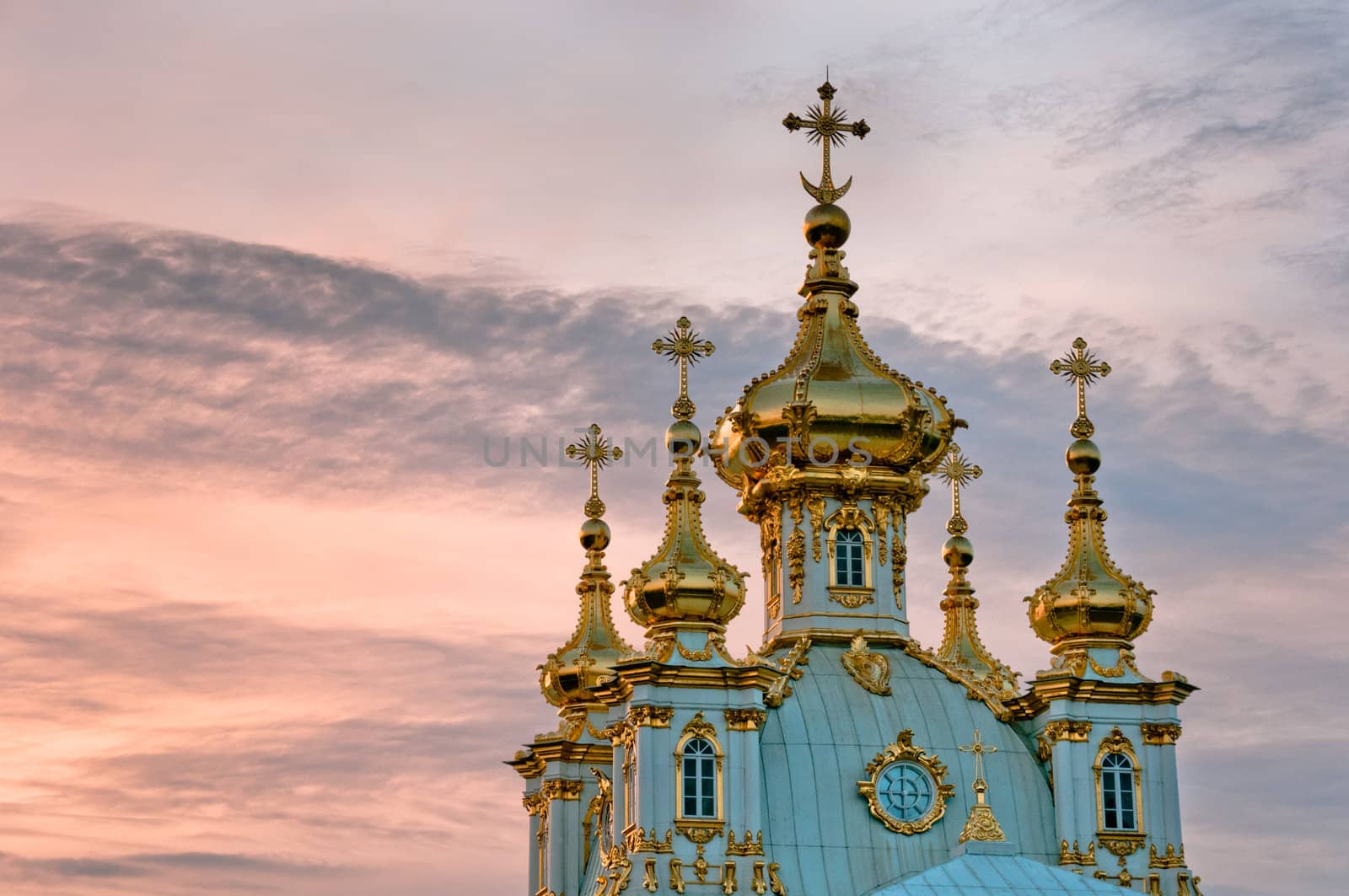 Golden domes of Petergof palace in park at twilight