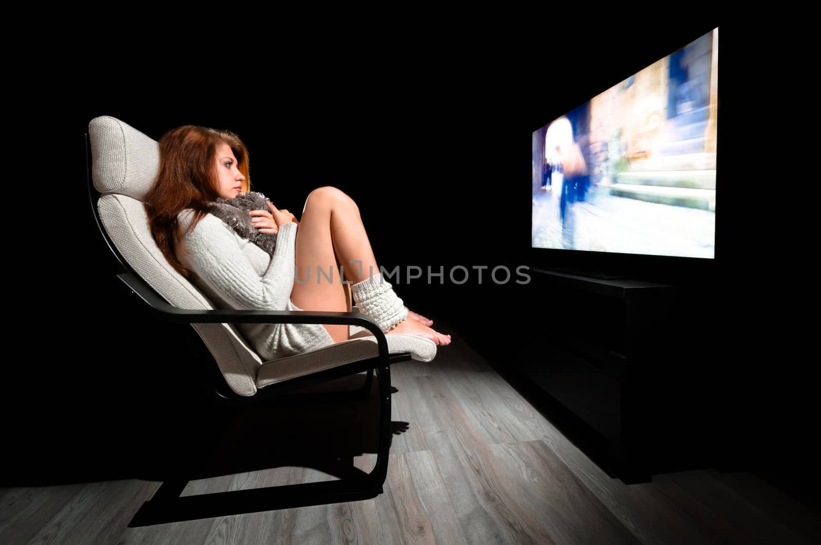 Girl sitting in front of large display in dark room with black background