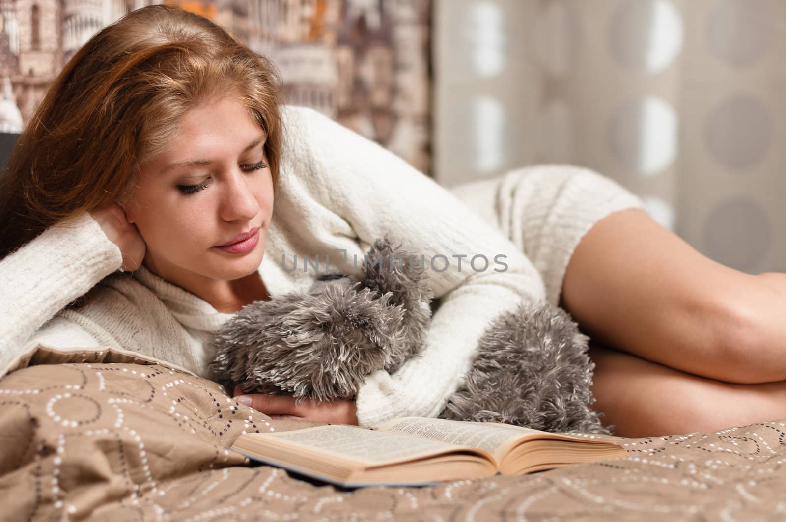 Pretty and cute woman reading a book while lying on bed