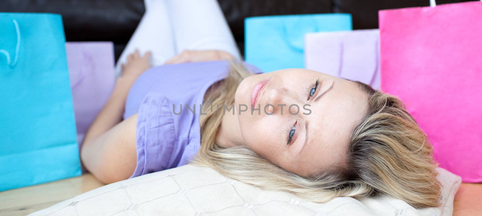 Tired woman after shopping lying on the floor  by Wavebreakmedia