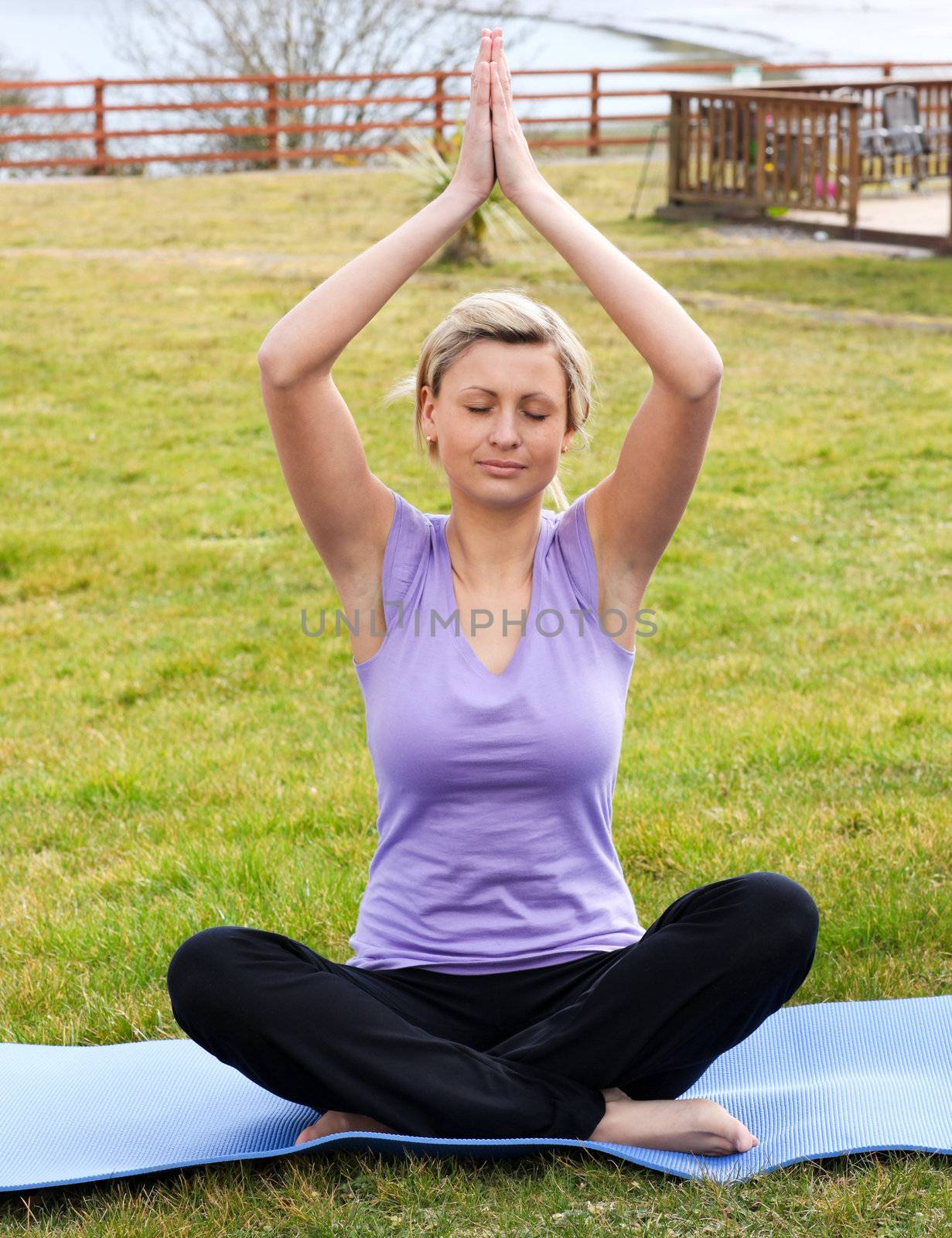 Relaxed woman doing yoga sitting on the grass in a park