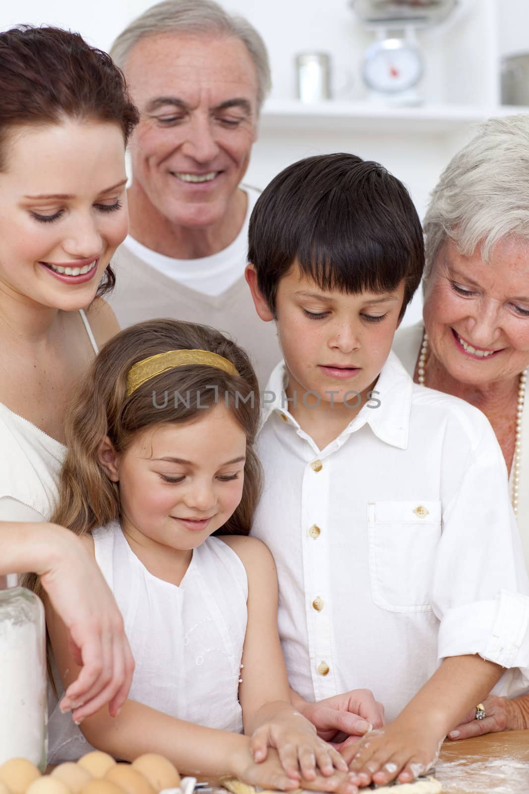 Grandparents looking at boy and a little girl baking in the kitchen