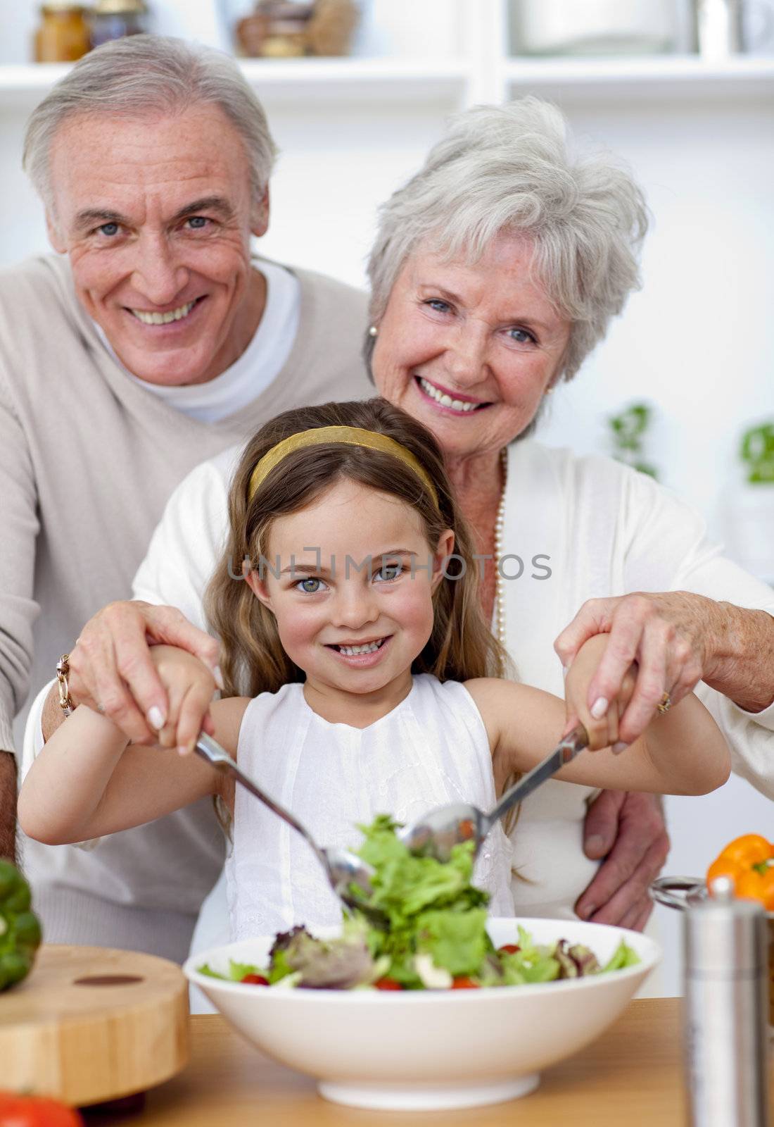 Smiling grandparents eating a salad with granddaughter by Wavebreakmedia
