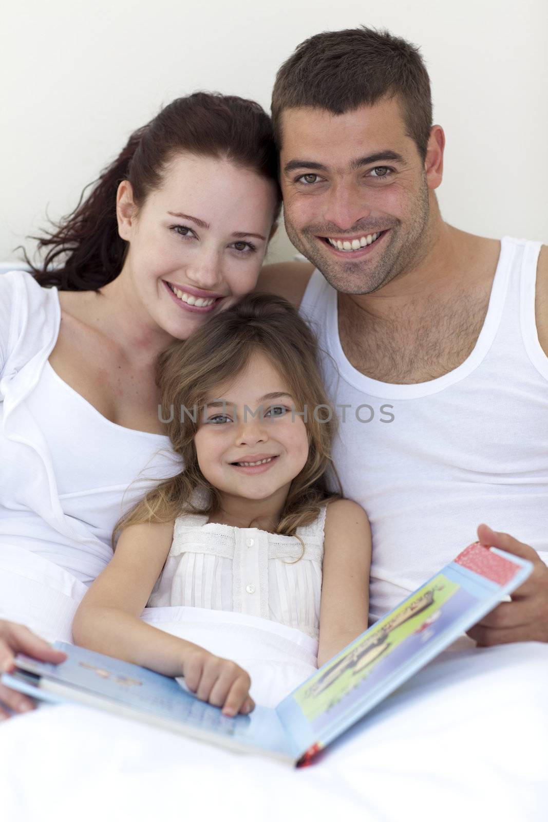 Portrait of parents and daughter reading together in bed