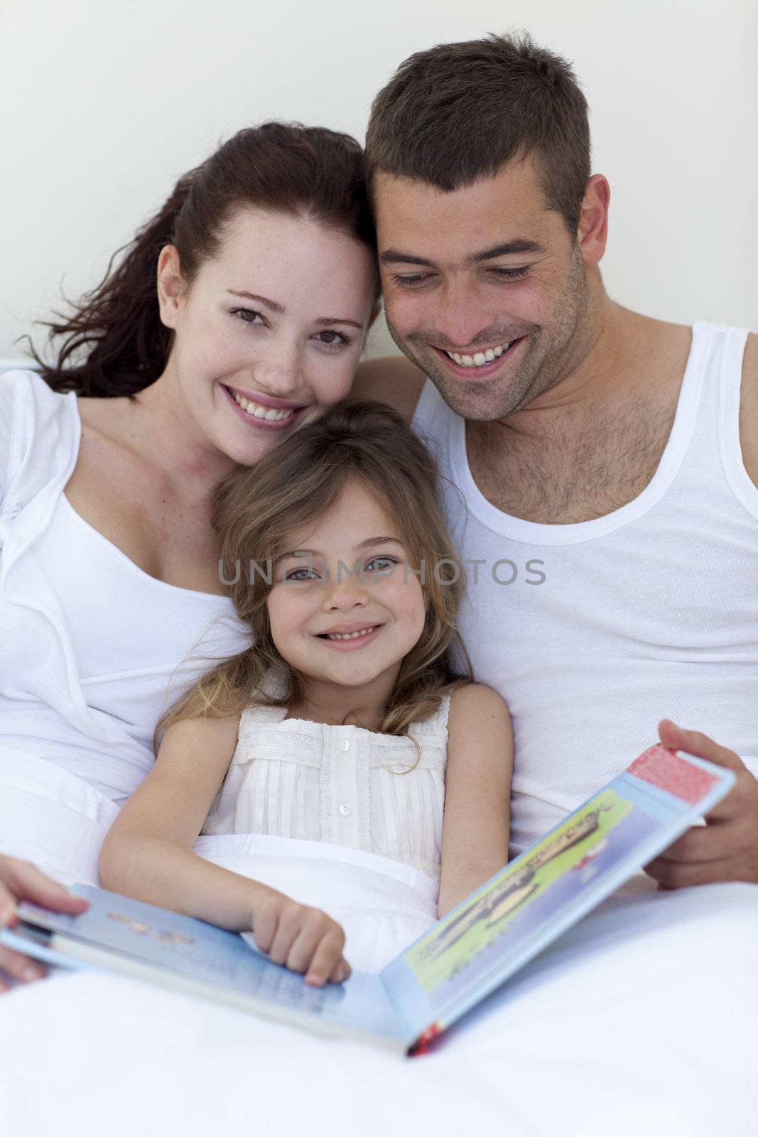 Parents and daughter reading in bed by Wavebreakmedia