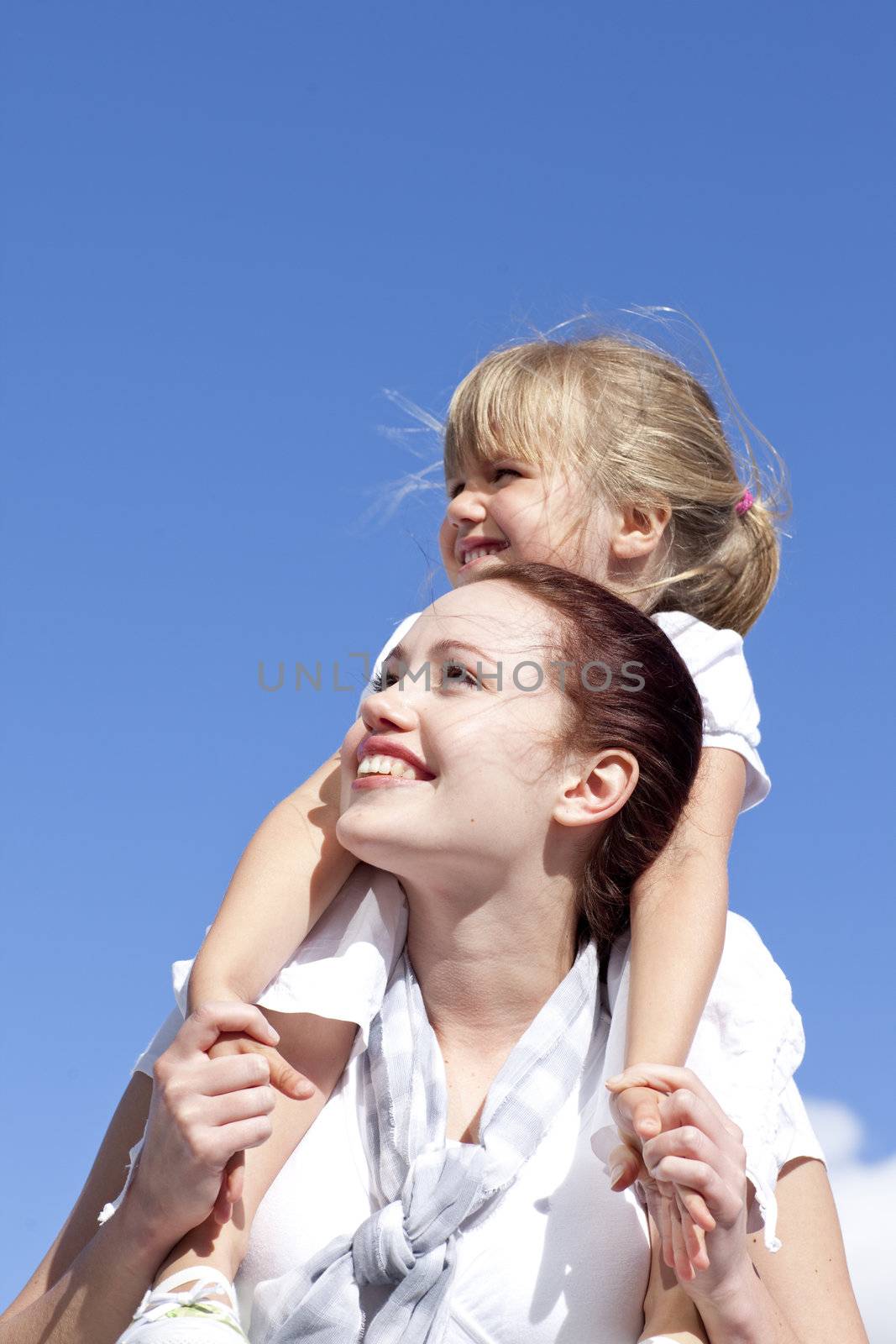 Attractive mother giving her daughter piggyback ride outdoors