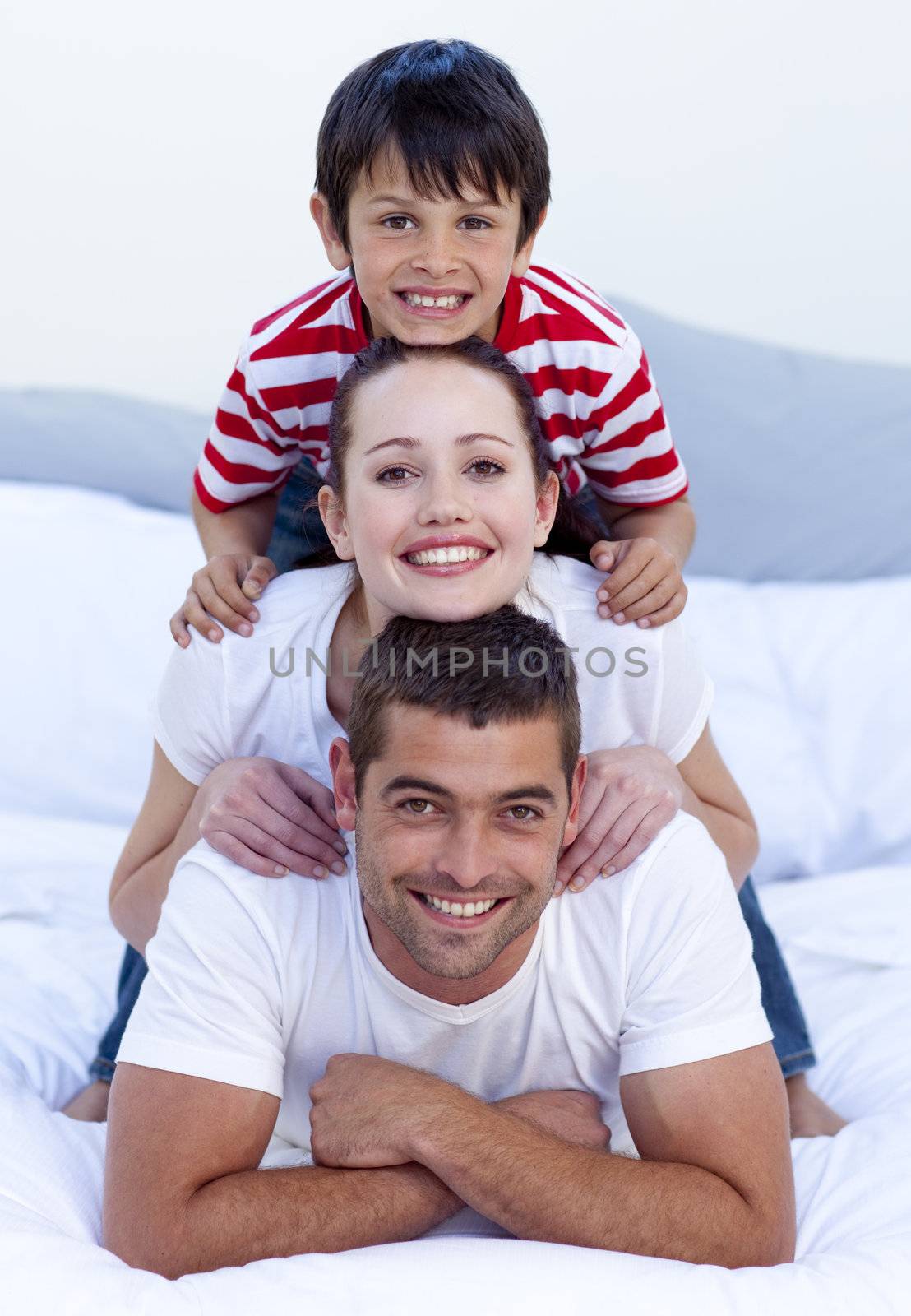 Happy parents and son playing in bed together