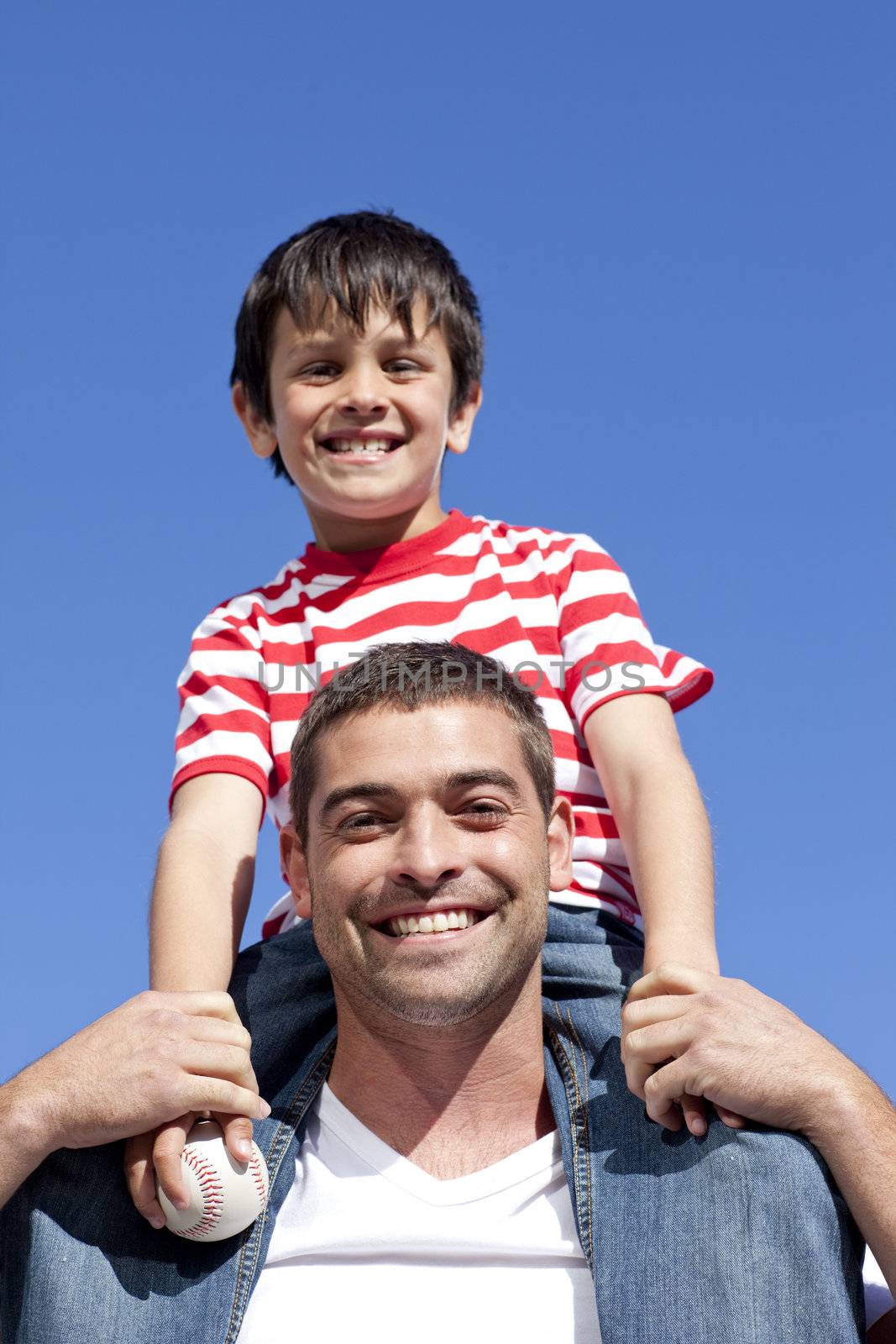 Father giving his son piggyback ride outdoors by Wavebreakmedia