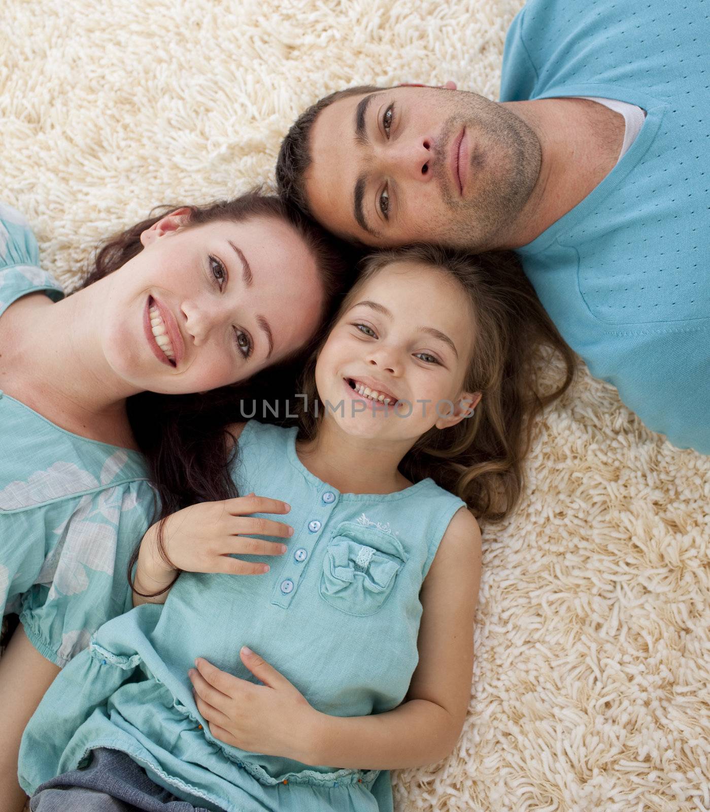 Portrait of parents and daughter on floor with heads together by Wavebreakmedia