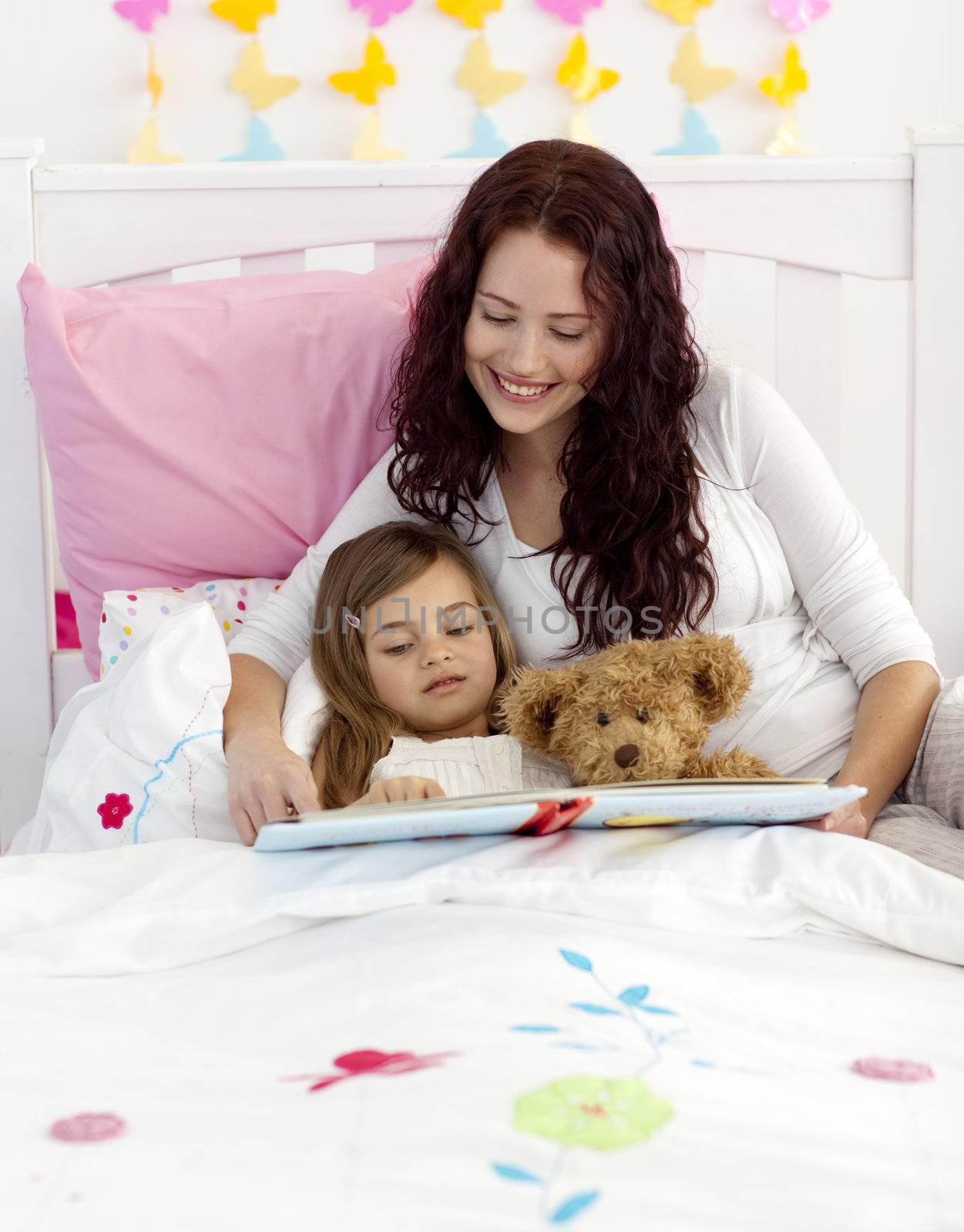 Mother and daughter reading a book together in bedroom