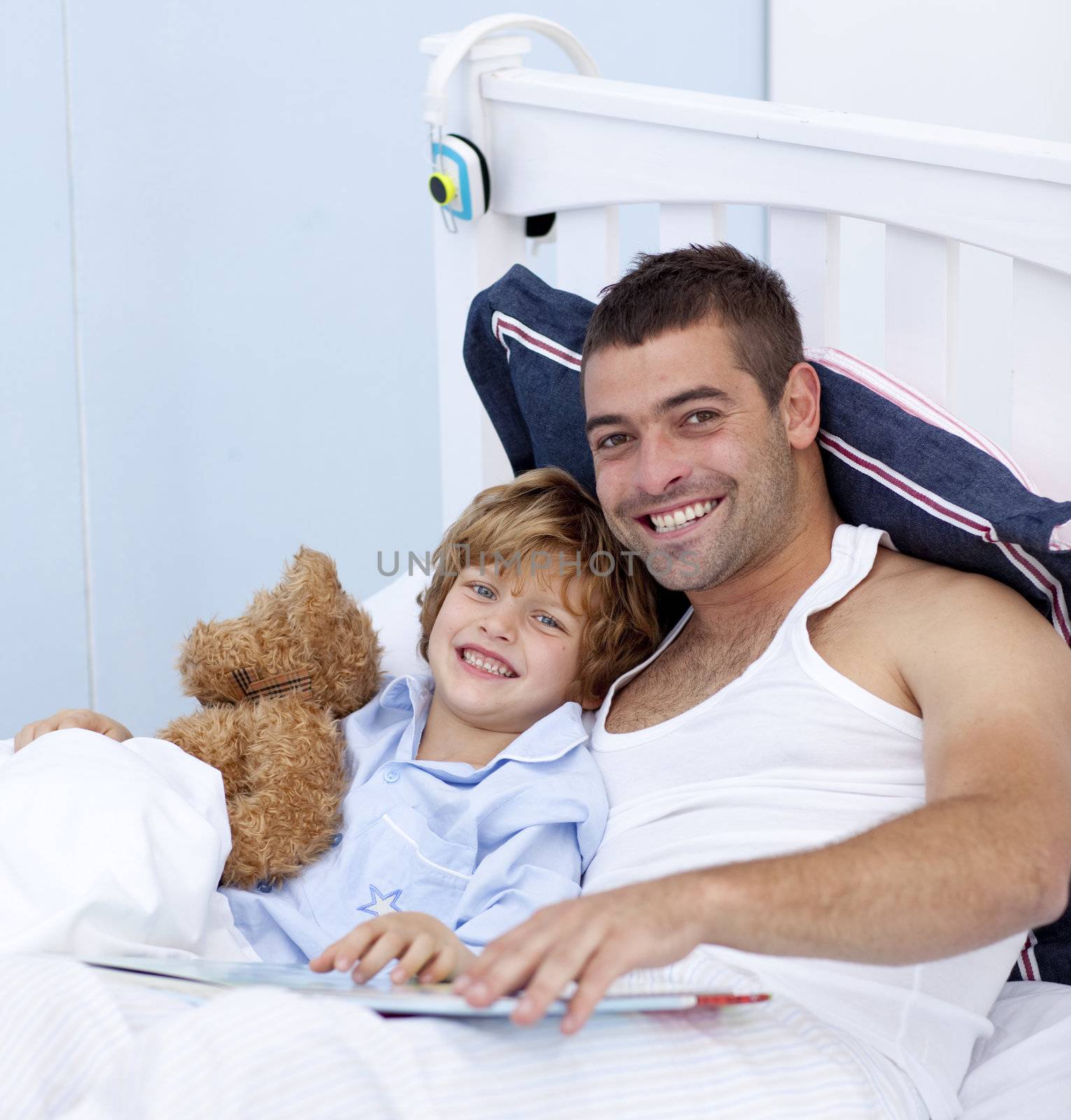 Smiling father and son reading a book in bed together