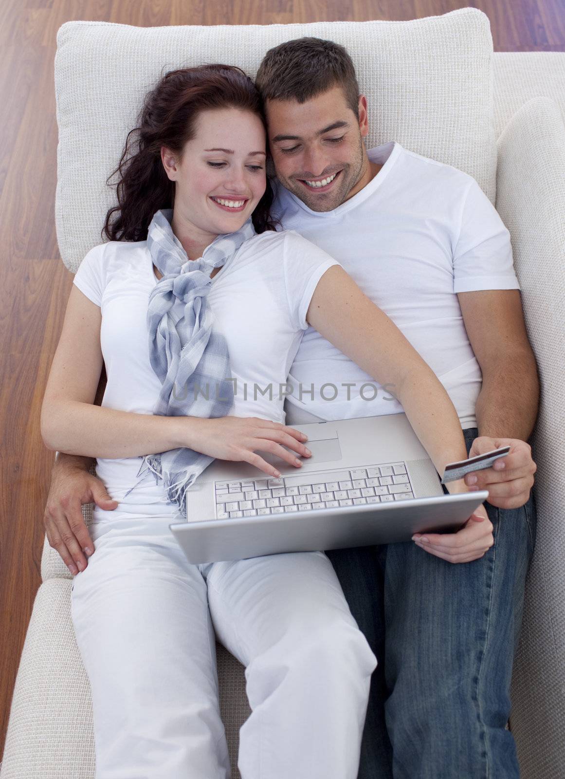 Family buying online with laptop and credit card on sofa