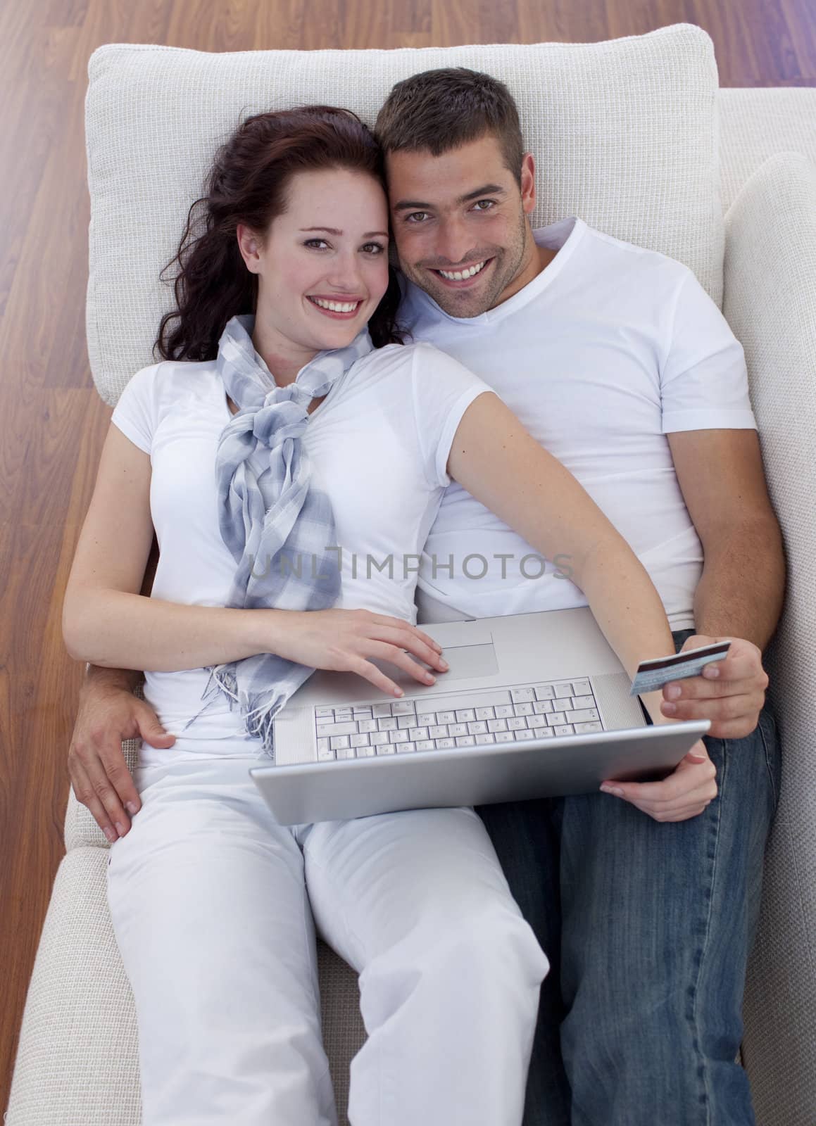 Family shopping online with laptop and credit card on sofa