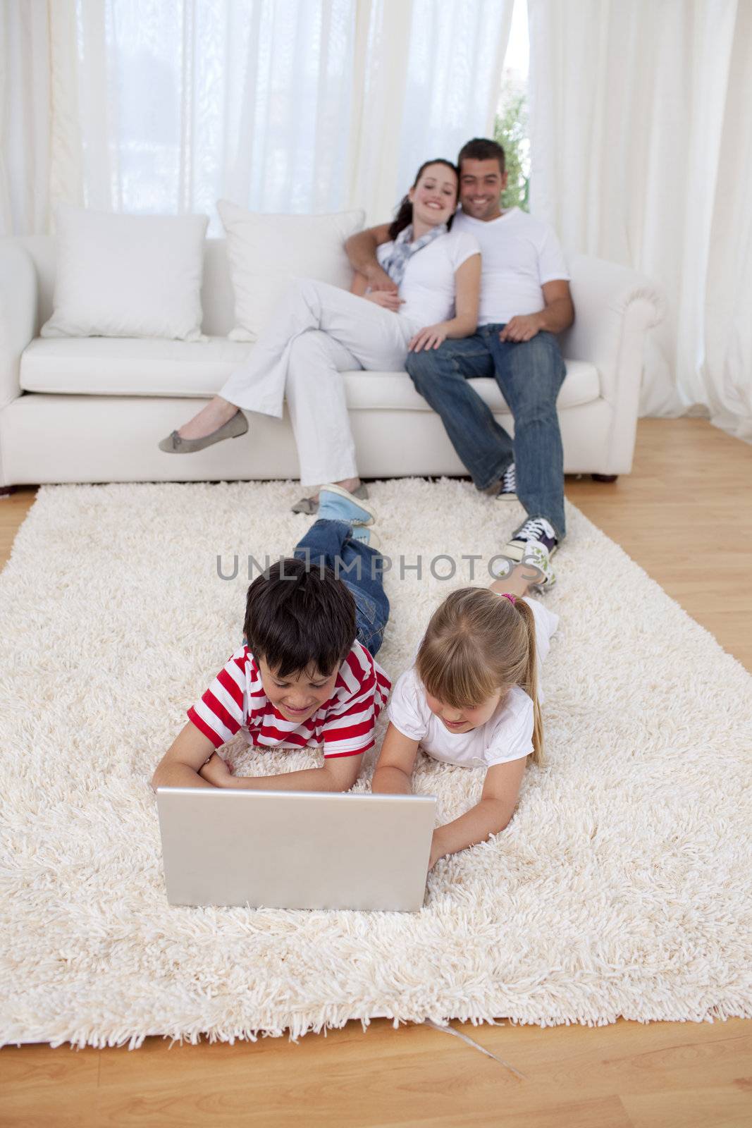 Brother and sister using a laptop on floor in living-room by Wavebreakmedia