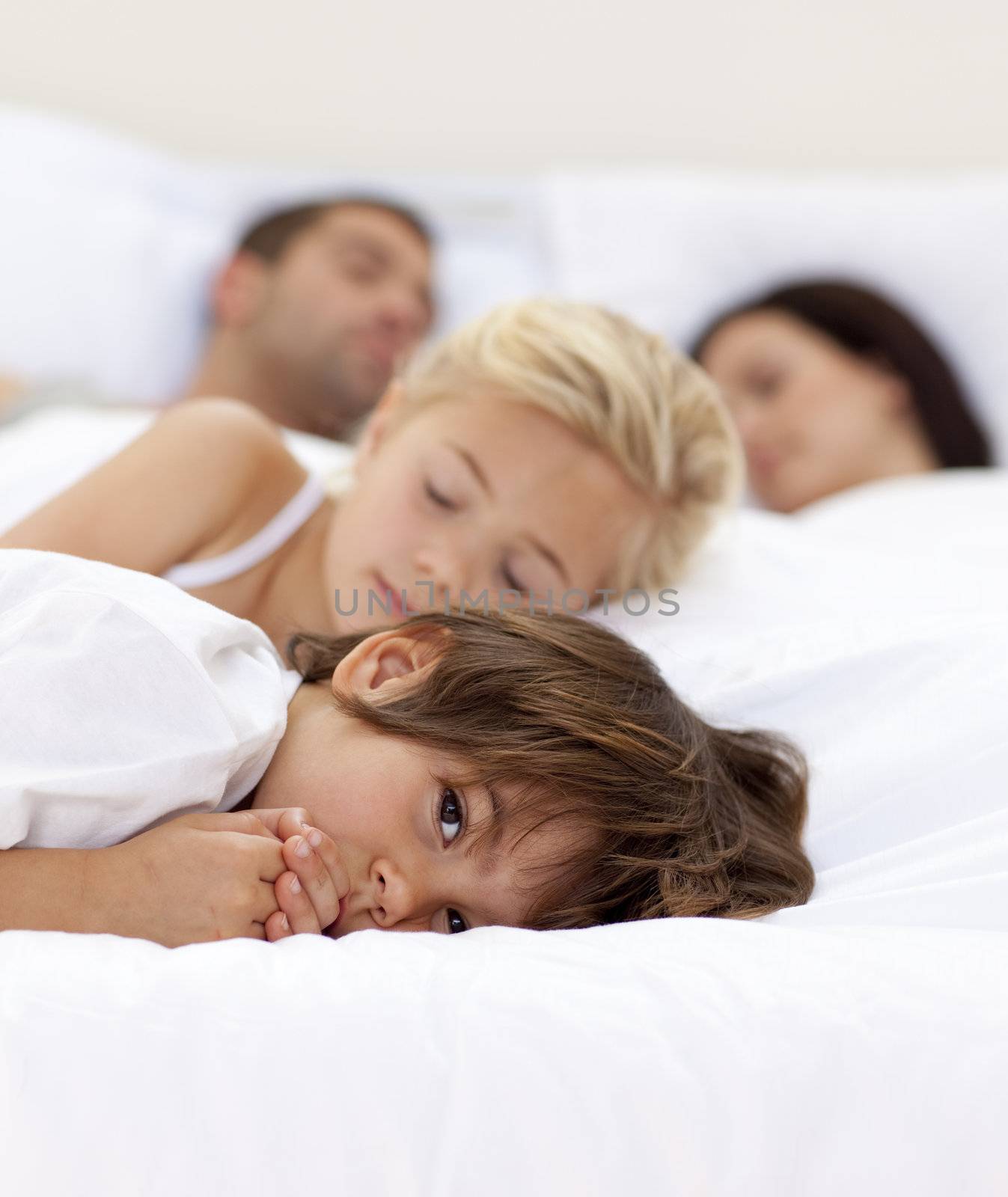 Little boy relaxing with his parents and sister sleeping by Wavebreakmedia
