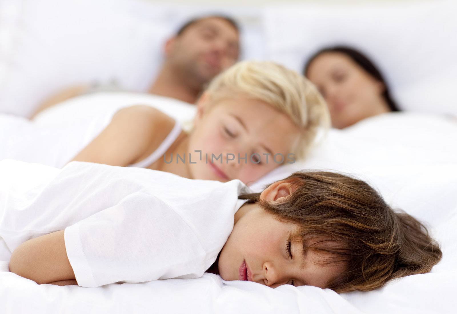 Children sleeping with his parents by Wavebreakmedia