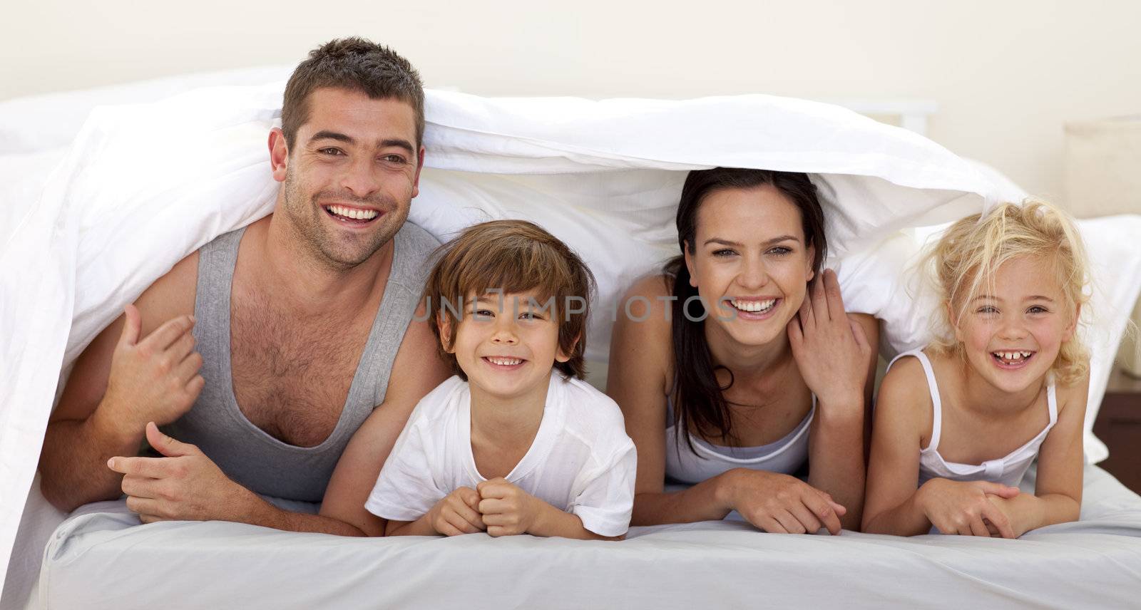 Parents and children playing in parent's bed by Wavebreakmedia
