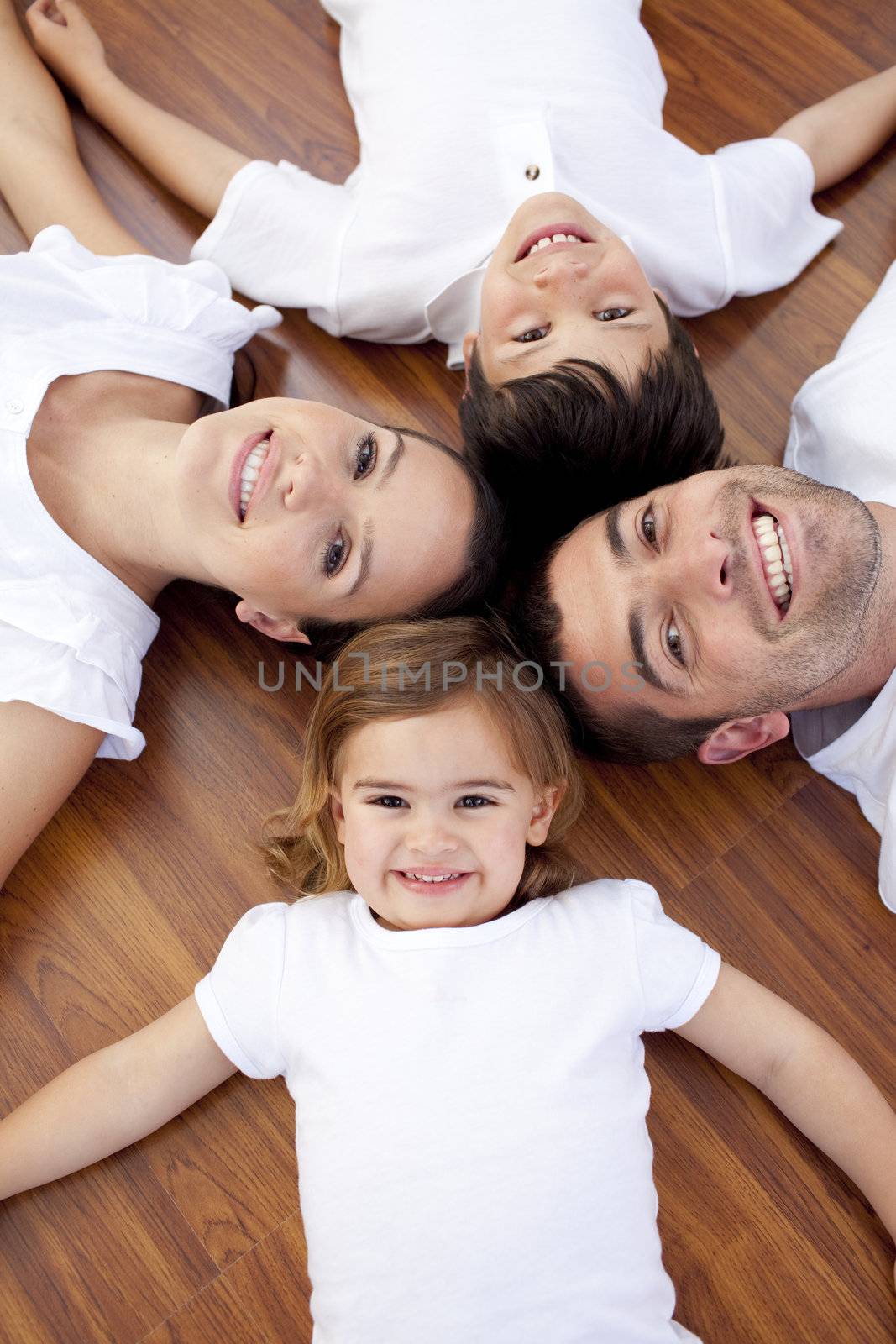 High angle of happy family lying on floor with heads together