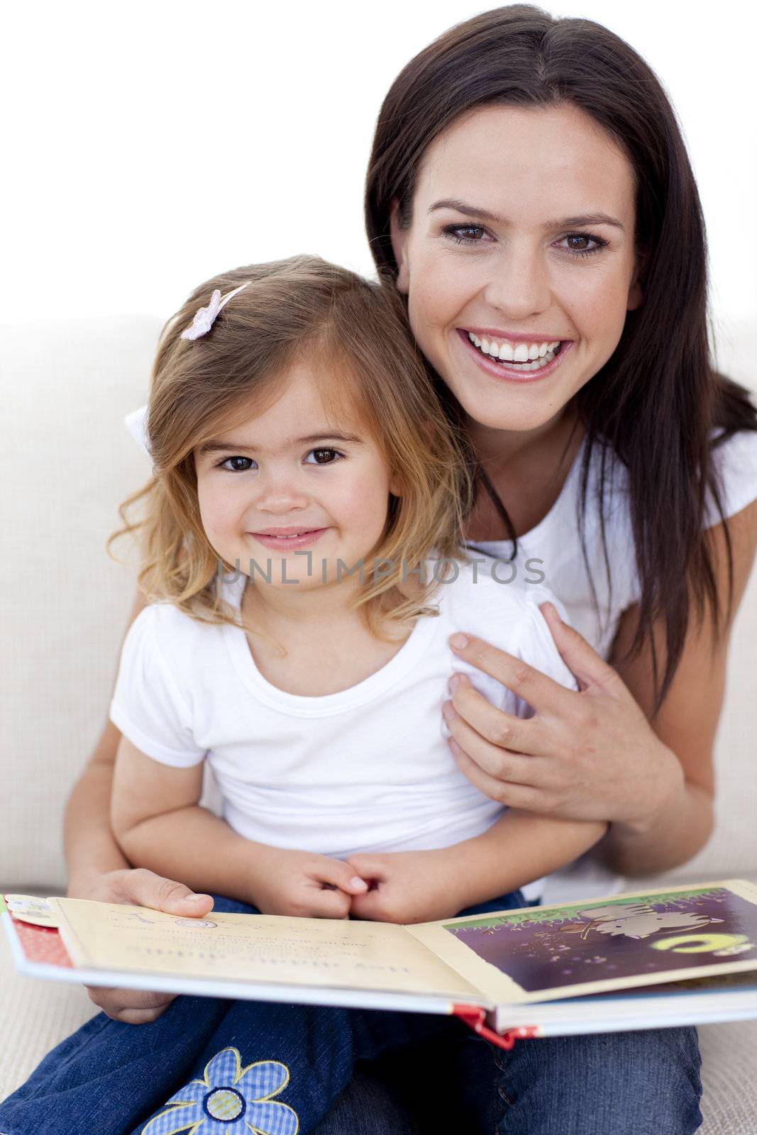 Smiling mother and daughter reading a book in living-room
