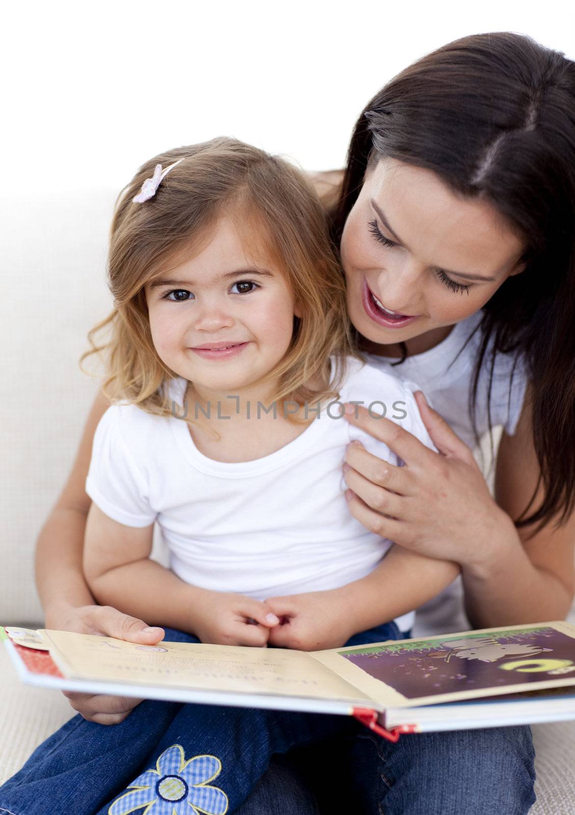 Little girl reading a book withher mother in living-room
