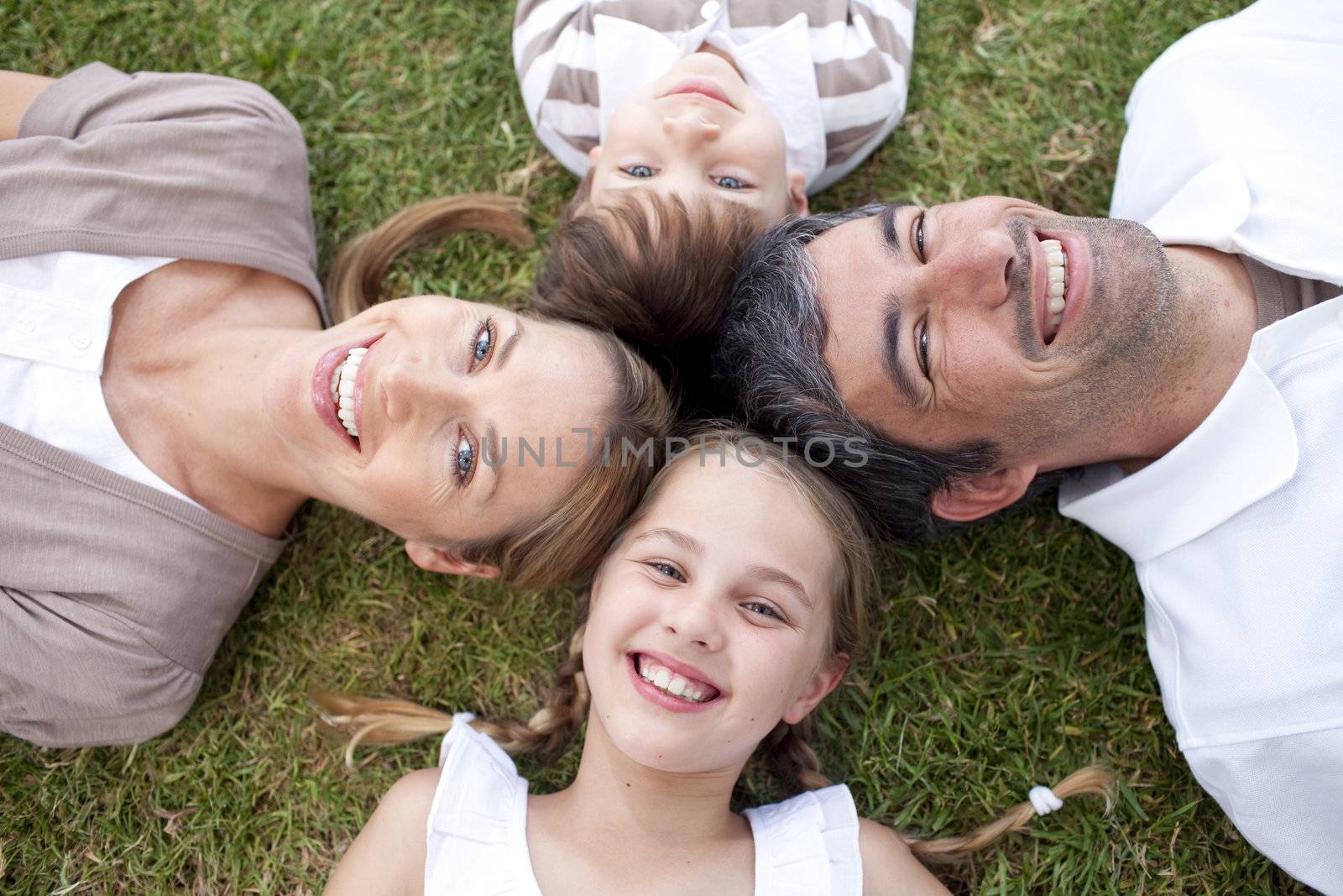 Smiling family lying outdoors with heads together