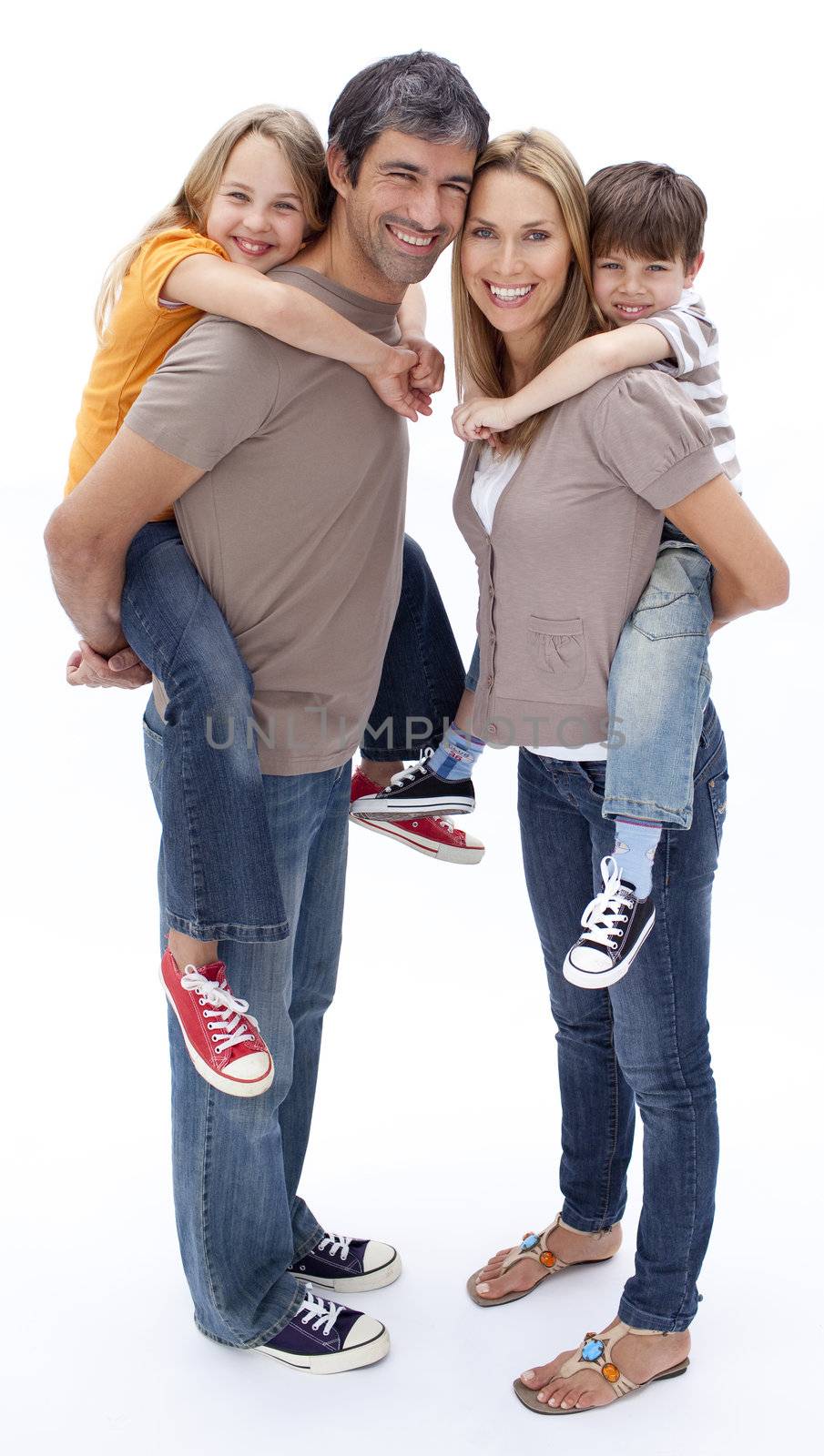 Parents giving children piggy back ride against white background