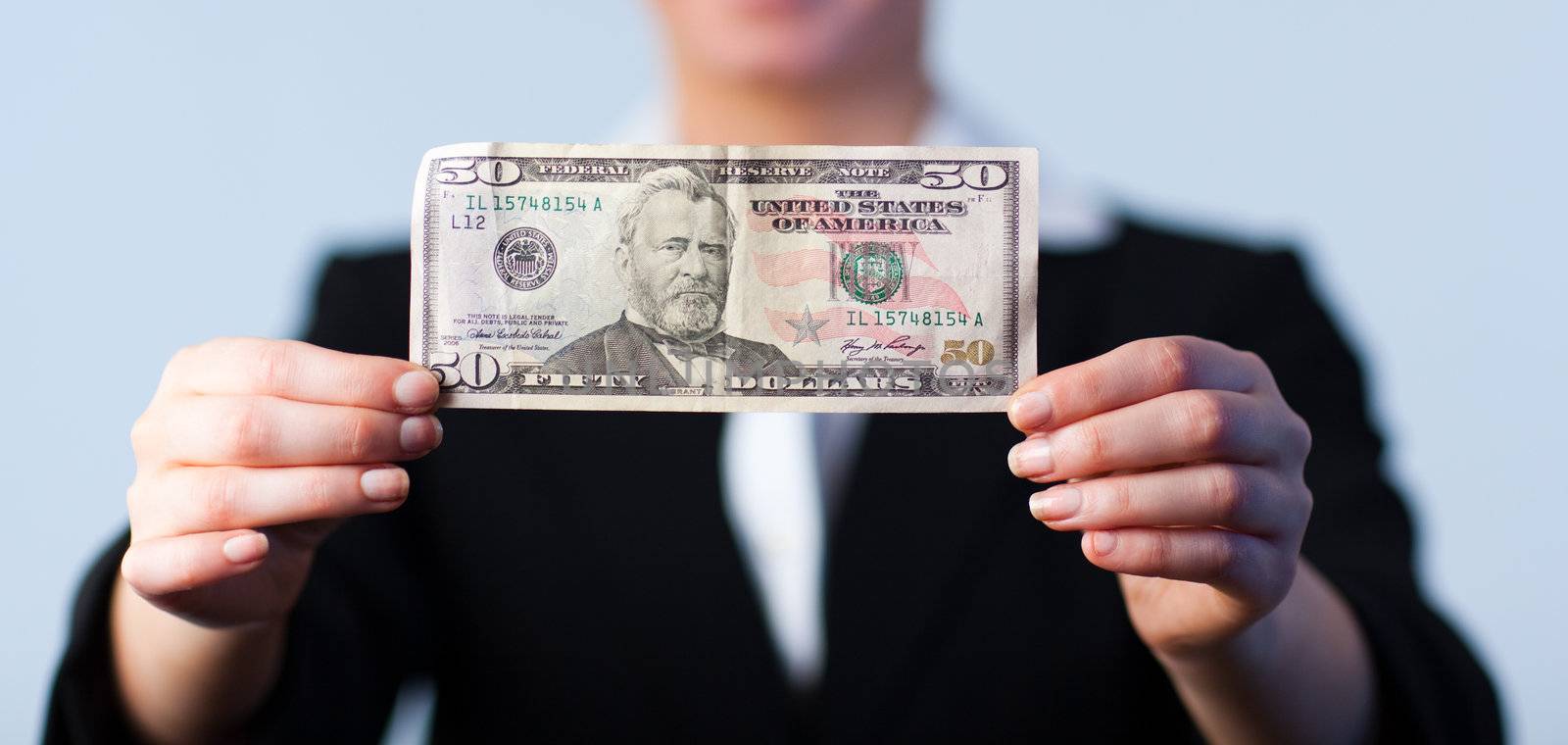 Business woman holding up dollars with camera focus on the dollars