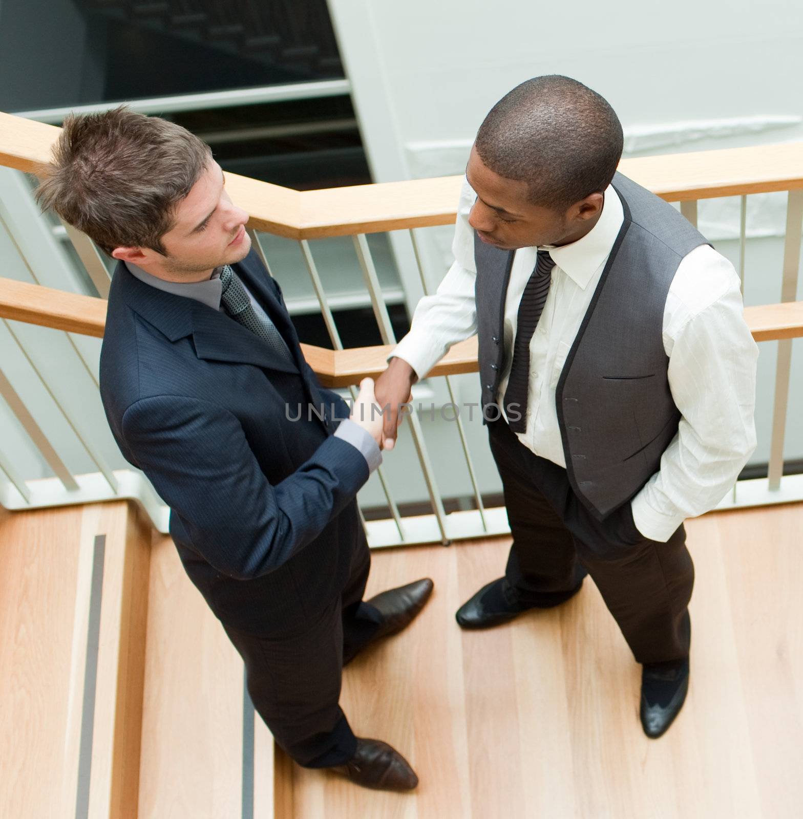 Two businessmen shaking hands on stairs by Wavebreakmedia