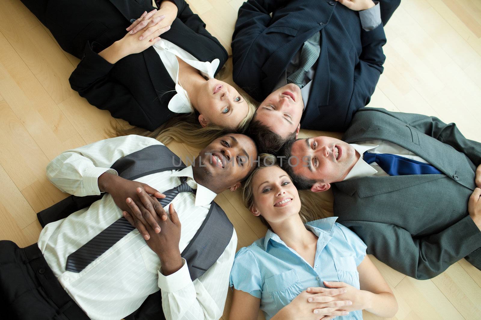 Business people lying in a circle on the floor of the office
