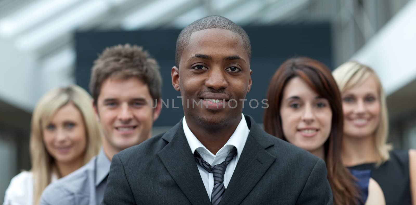Afro-American businessman smiling at the camera with his team  by Wavebreakmedia