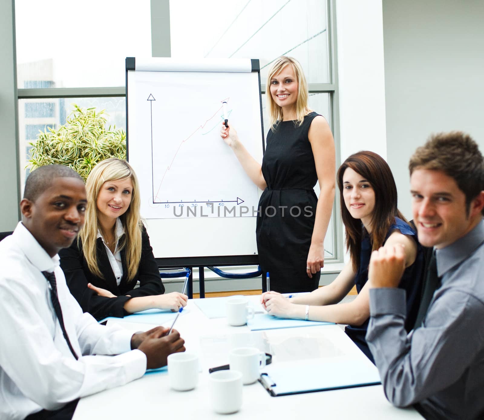 Attractive businesswoman giving a presentation to her team smiling at the camera